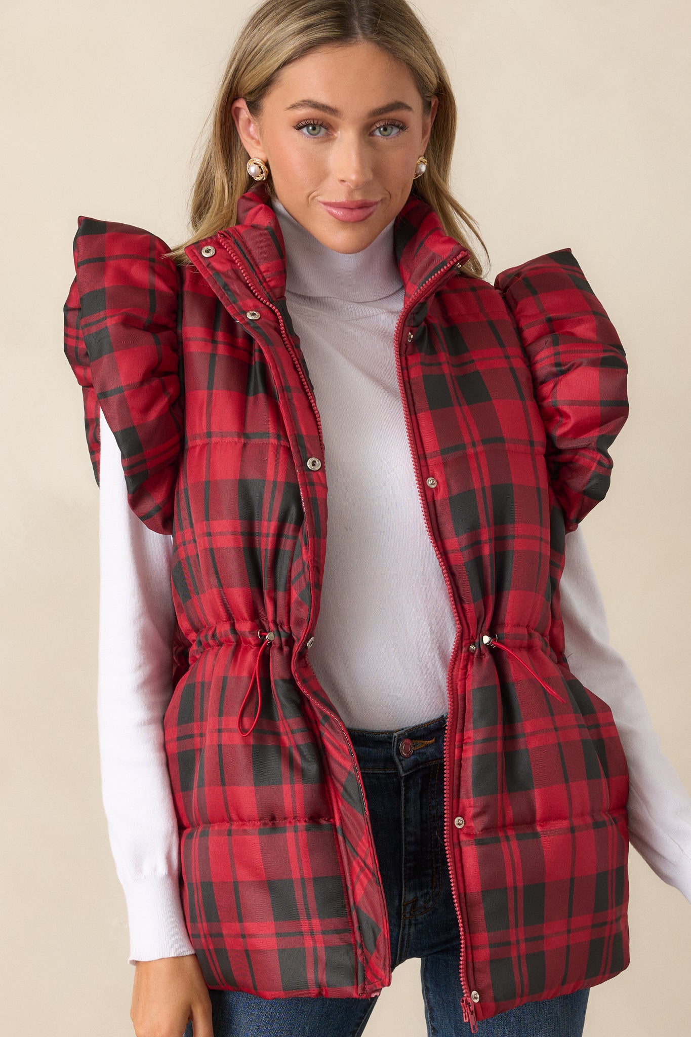 Another view of the red puffer vest emphasizing the functional snap button and zipper closures and the drawstring cinch waist with silver hardware.