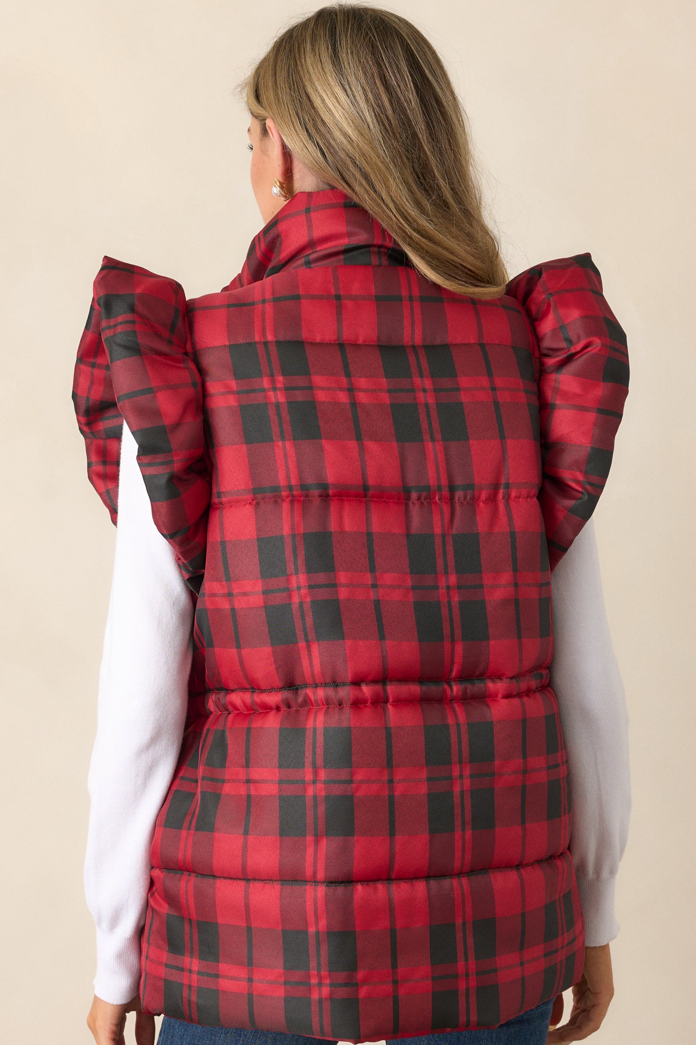 Full back view of the red puffer vest, emphasizing the plaid pattern, puffer line detailing, and cinched waist design.