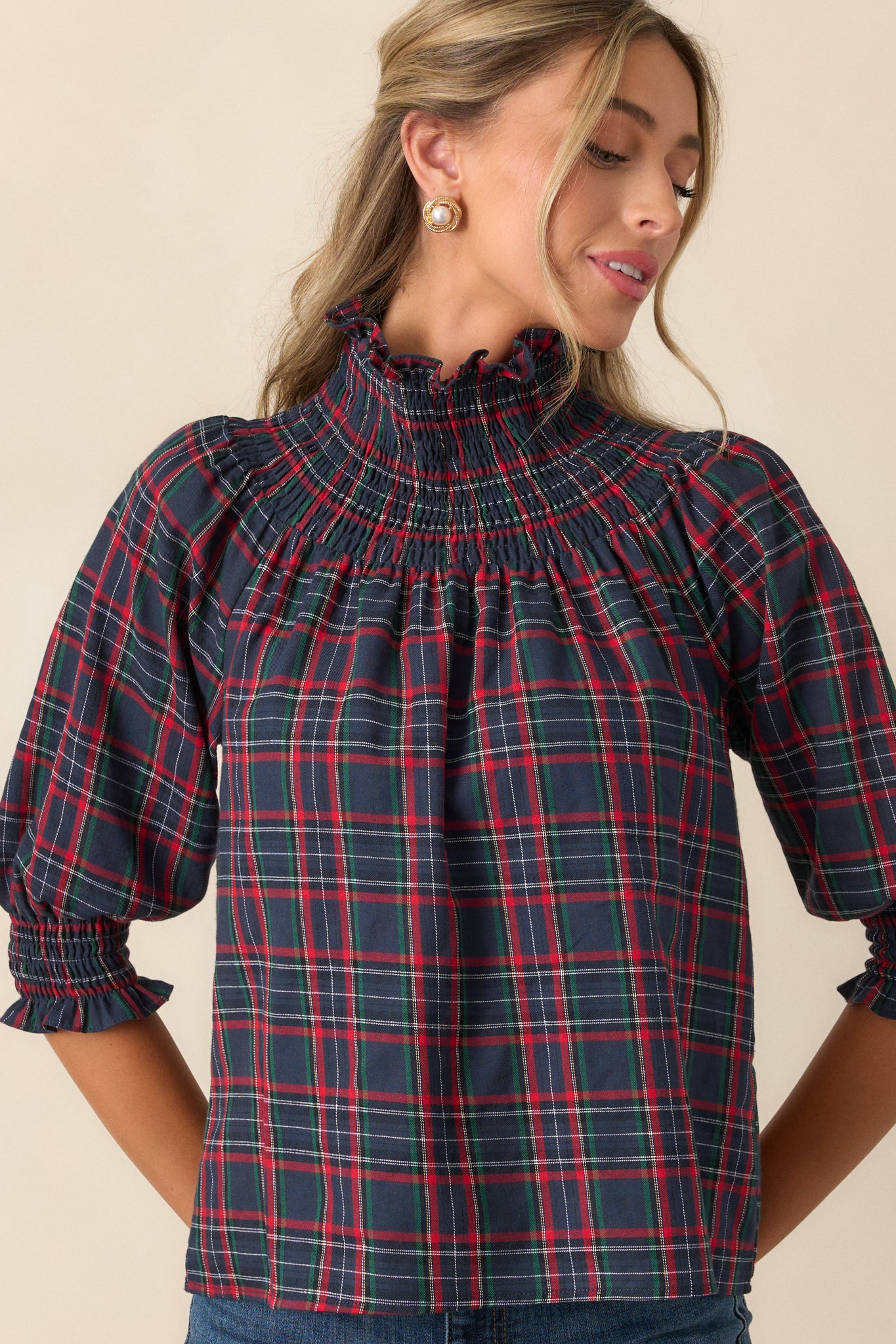 Close-up of the high smocked neckline and puff sleeves, showing the detailed smocking work and the texture of the plaid print.