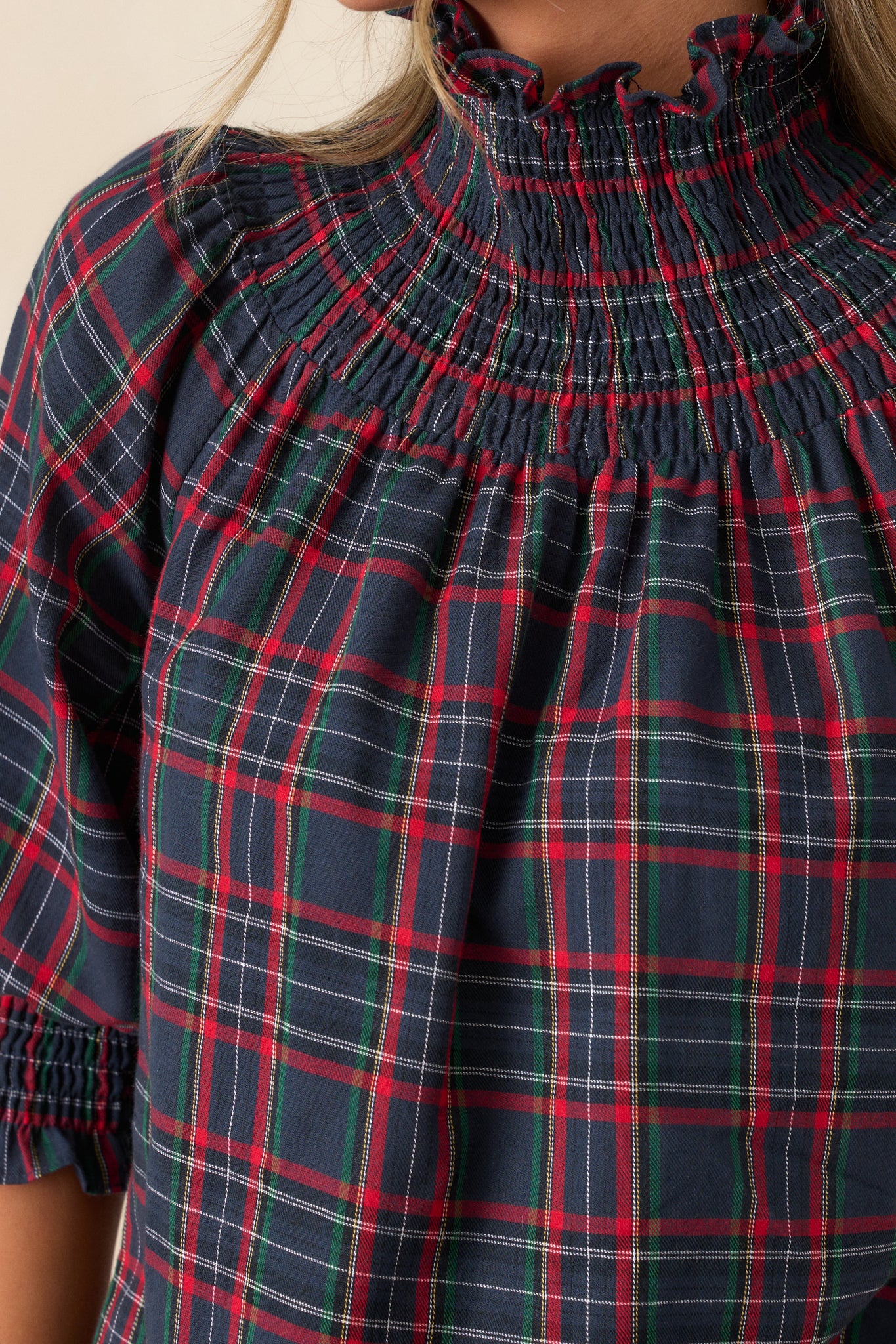 Close-up of the smocked neck and fabric, highlighting the detailed smocking technique, the soft texture of the blouse, and the rich plaid design.