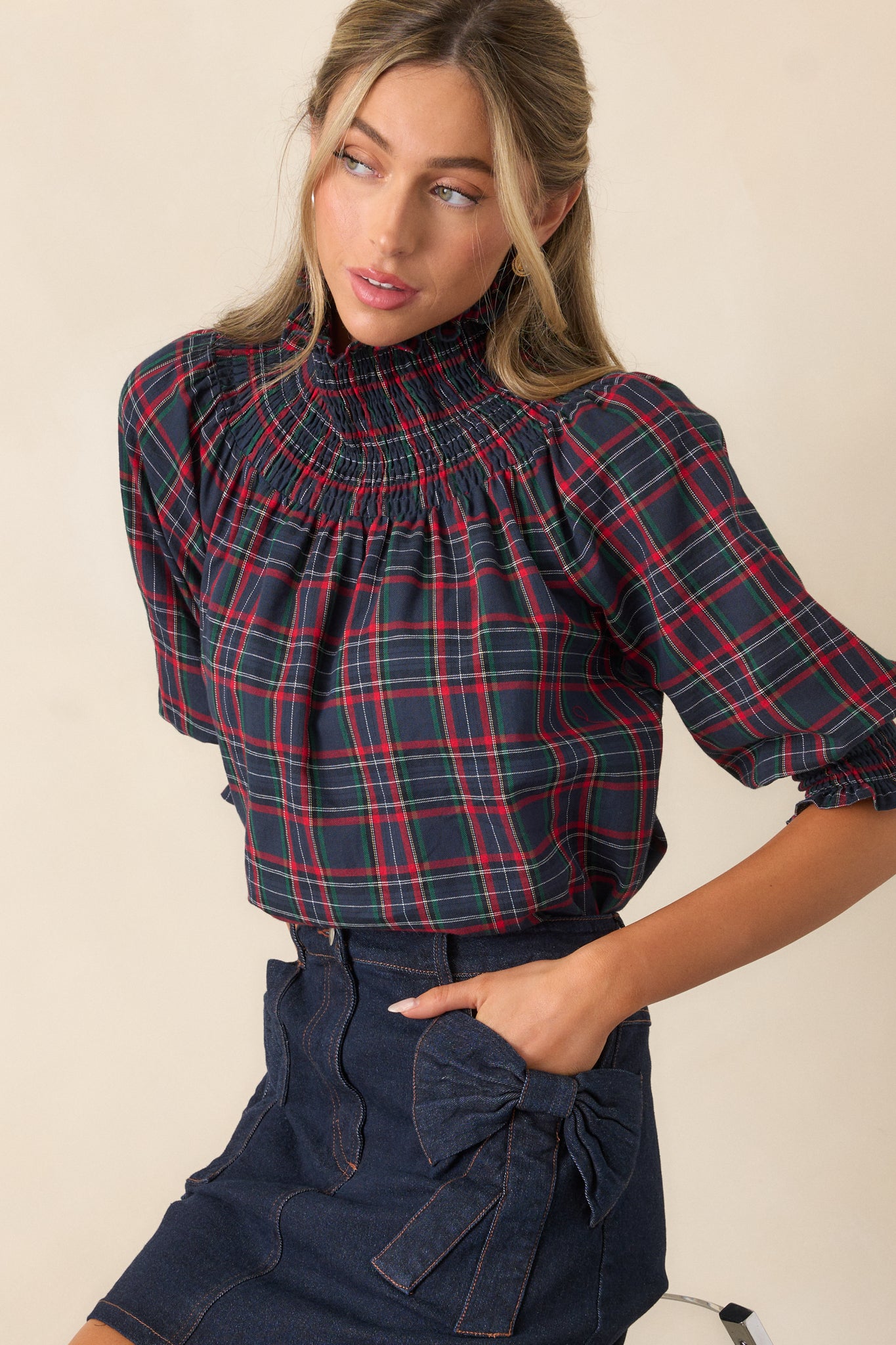 Three-quarter angle of the navy blouse, highlighting the relaxed fit, smocked neck, puff sleeves, and smocked cuffs, with the plaid pattern complementing the design.