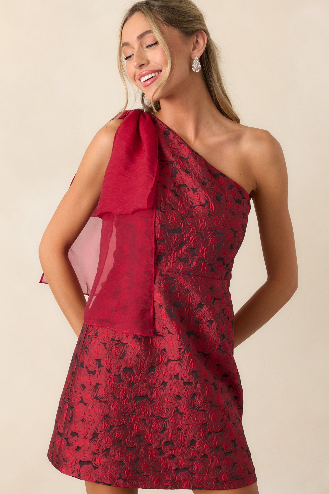 A close view of the upper portion of the dress, focusing on the one-shoulder neckline and the intricate bow detail.