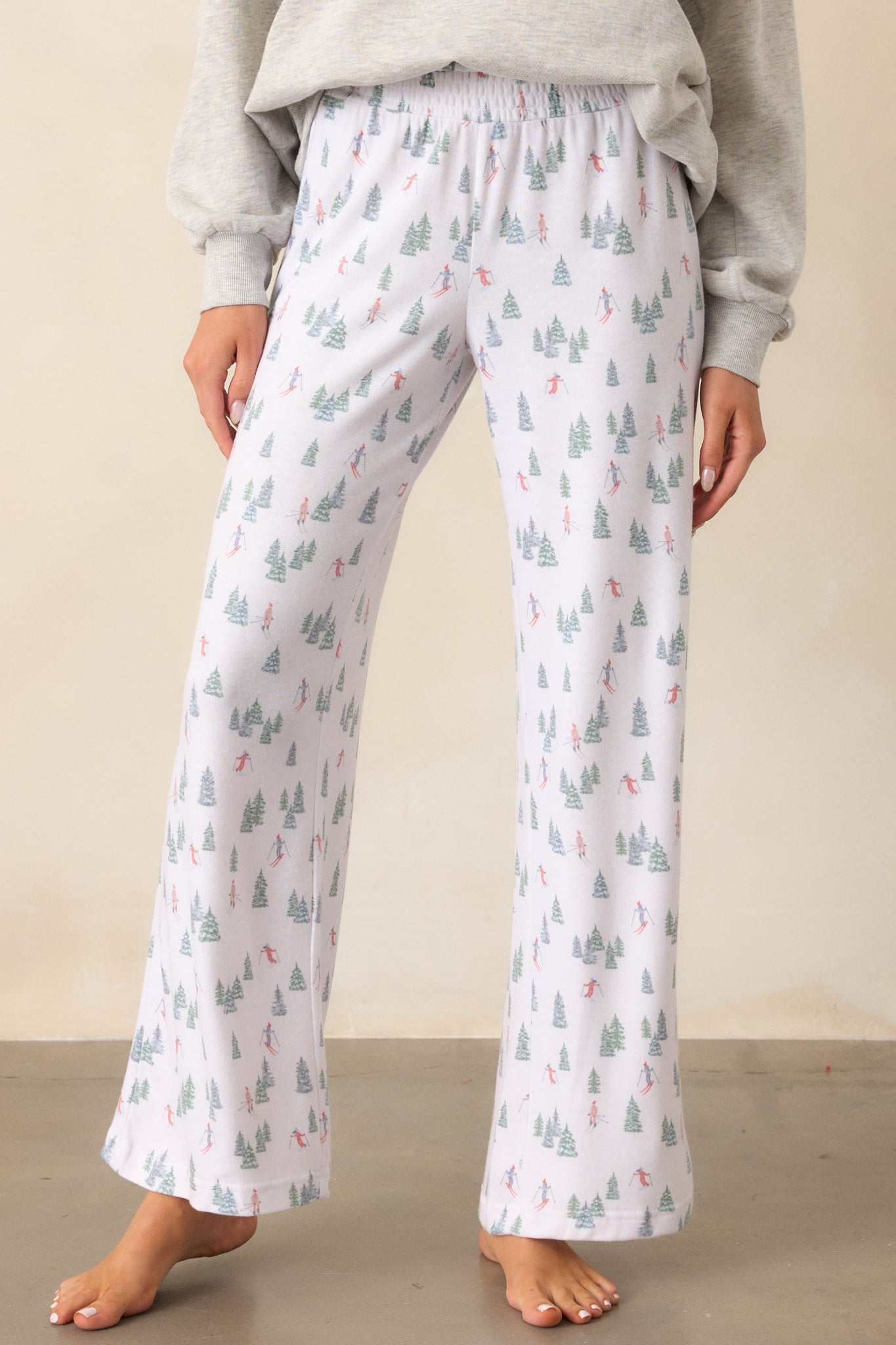 A cropped view of the waist and hips of the ivory pants, focusing on the smocked waistband and the alpine skier pattern along the fabric.