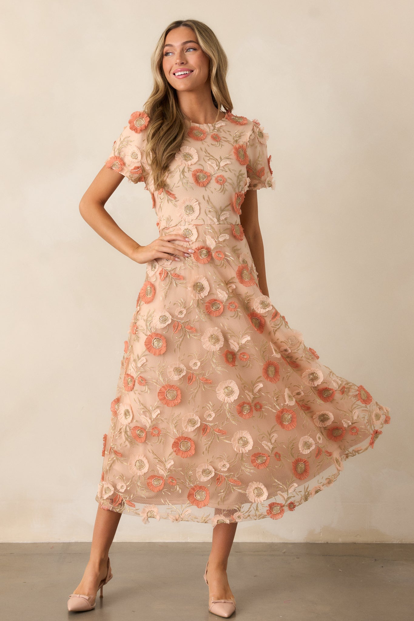 Full view of the tan dress showcasing the floral embroidery, short sleeves, and the airy movement of the flared skirt in a flattering fit-and-flare silhouette.