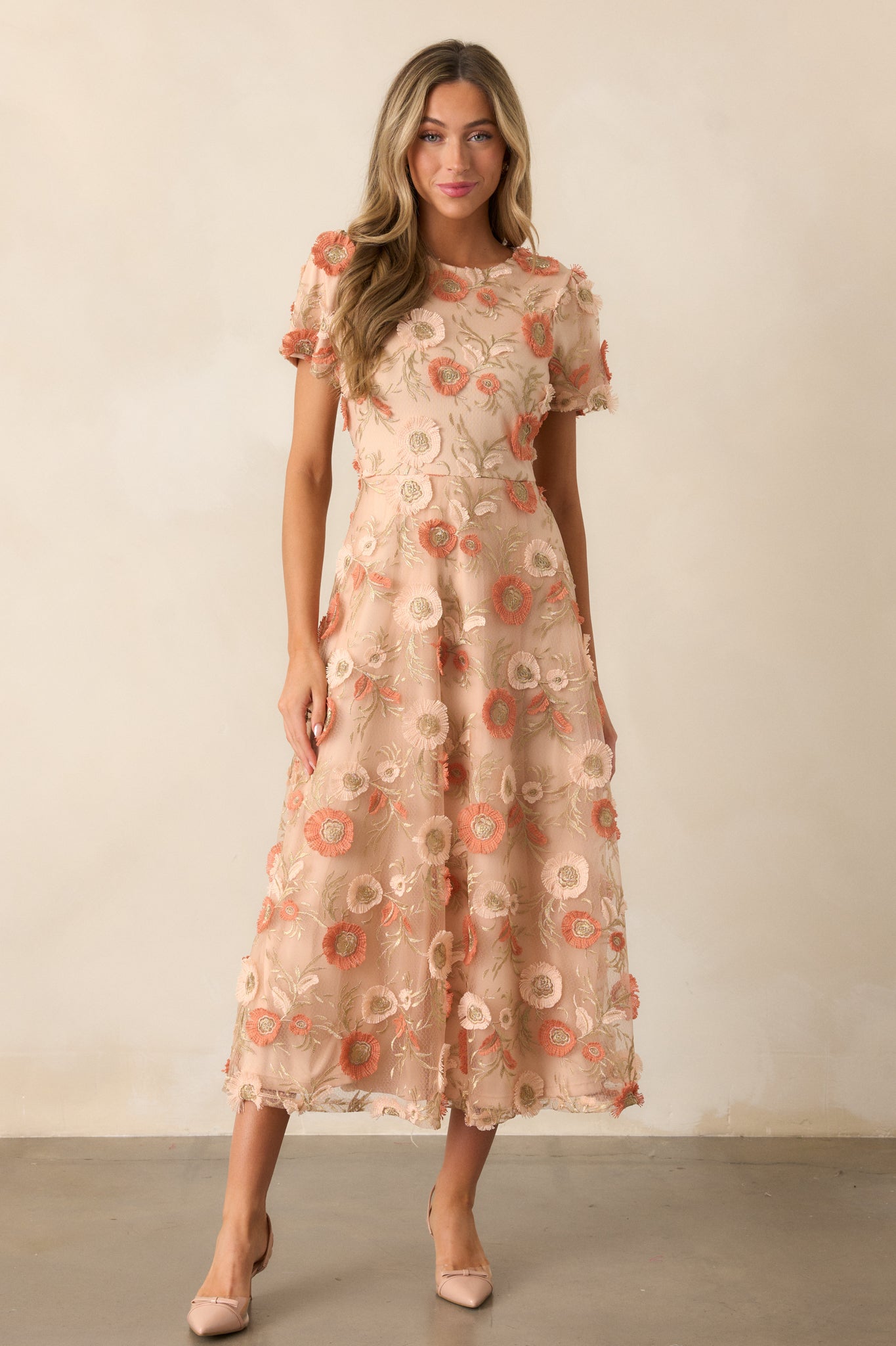 Another full-body shot of the tan dress with round neckline, intricate floral embroidery, and the flowing fit-and-flare silhouette complemented by short sleeves.