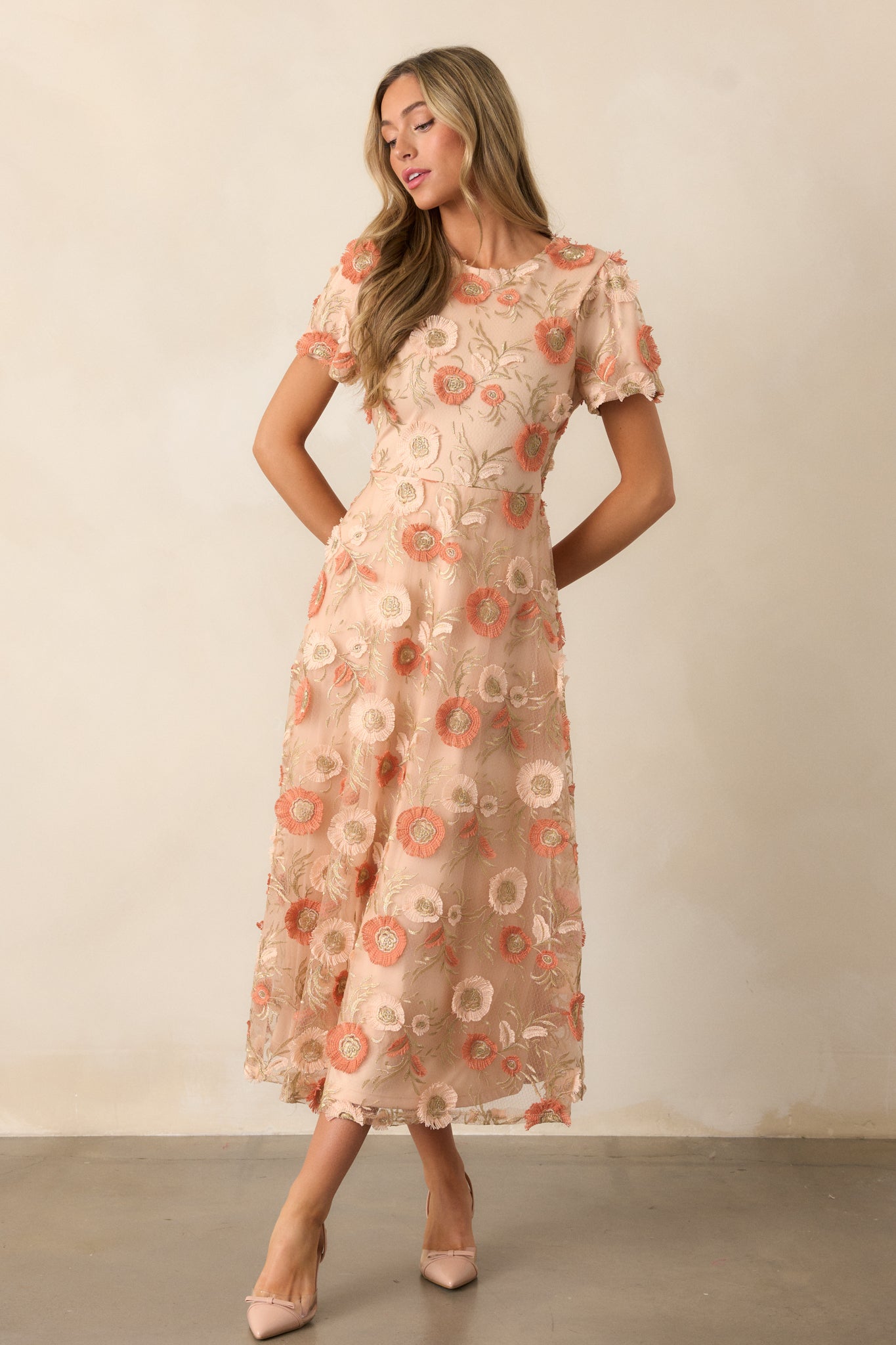 Front view of the tan dress featuring a round neckline, delicate floral embroidery, and a flattering fit-and-flare design with short sleeves.