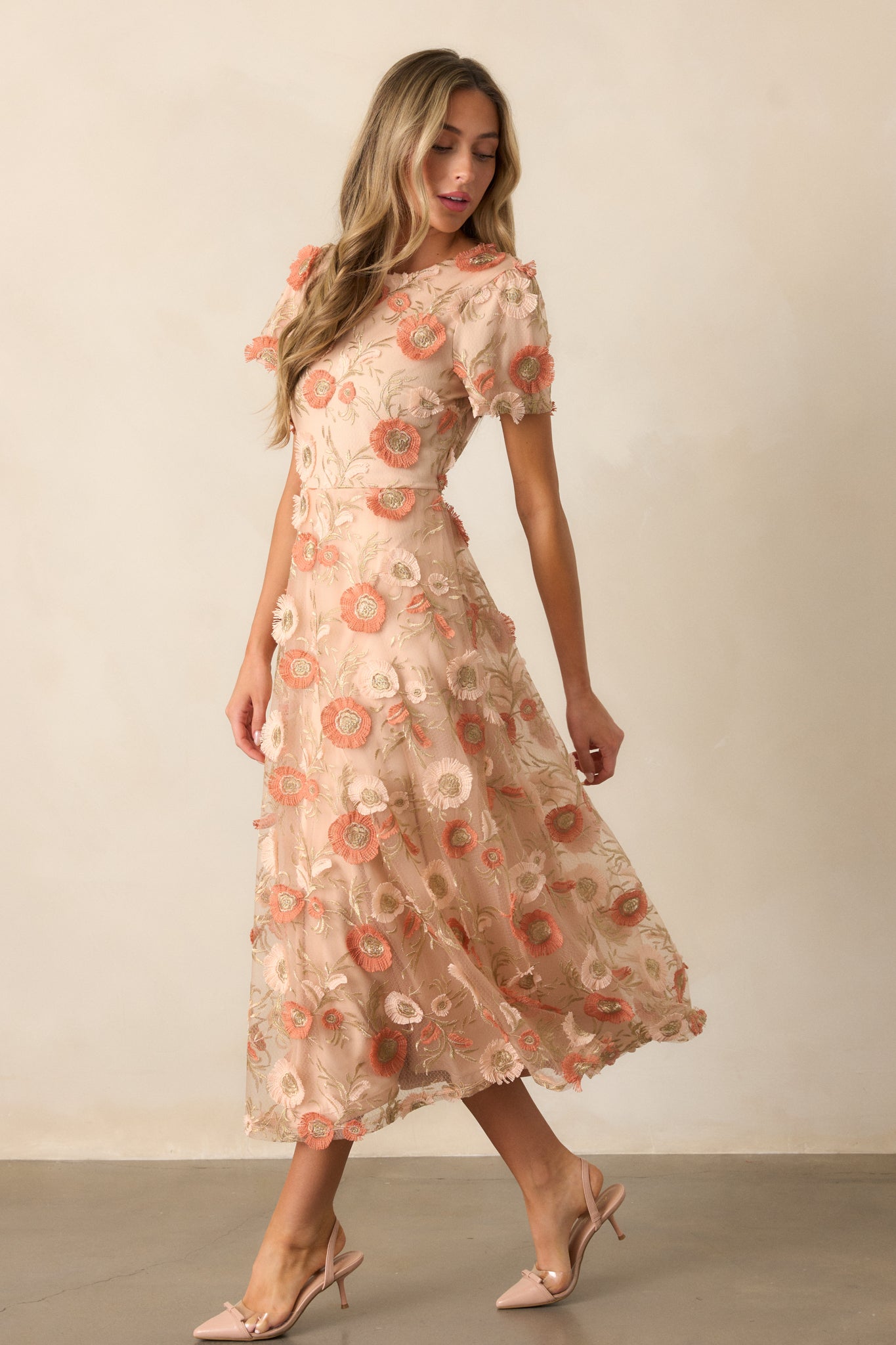 Side view of the tan dress showcasing the embroidered floral overlay, the fit-and-flare shape, and flow of the silhouette.