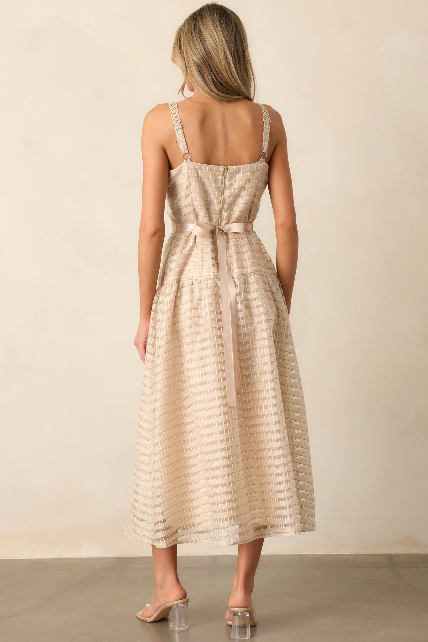 Back view of the tan dress, highlighting the gold back zipper detailing and embroidered adjustable straps. The embroidered pattern across the back adds texture, and the ribbon waist detailing can be seen from behind, emphasizing the dress's feminine silhouette.