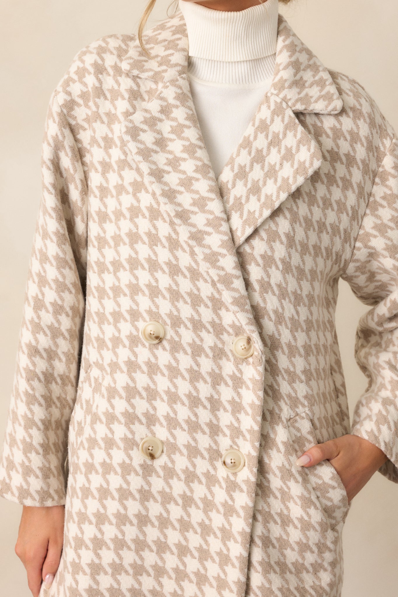 Close-up of the beige trench coat’s lapel neckline and houndstooth print. The button detailing and texture of the fabric are clearly highlighted.