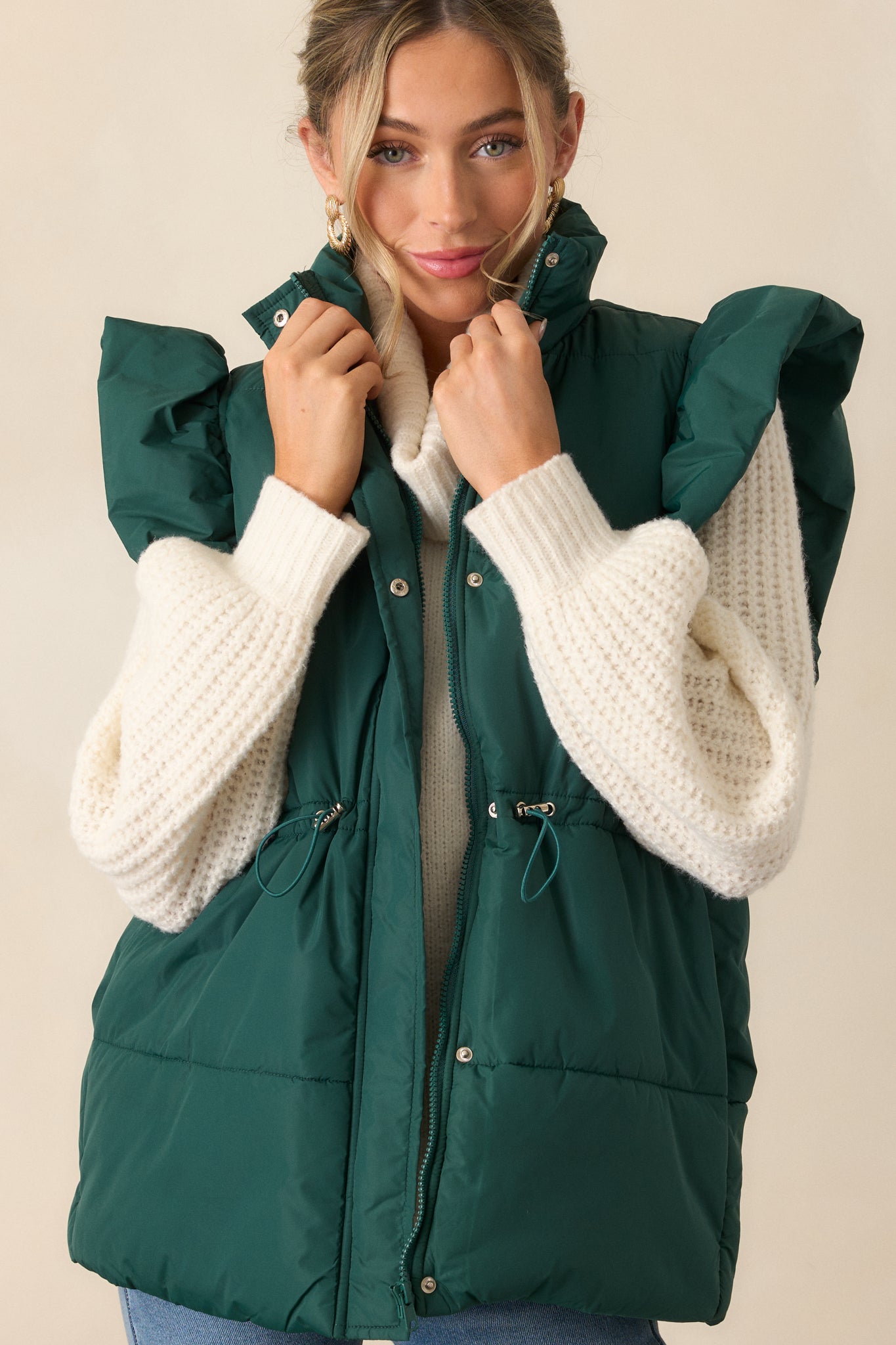 Detailed view of the vest’s fluffy flutter sleeves and the high neckline. The puffer line detailing can be seen clearly.