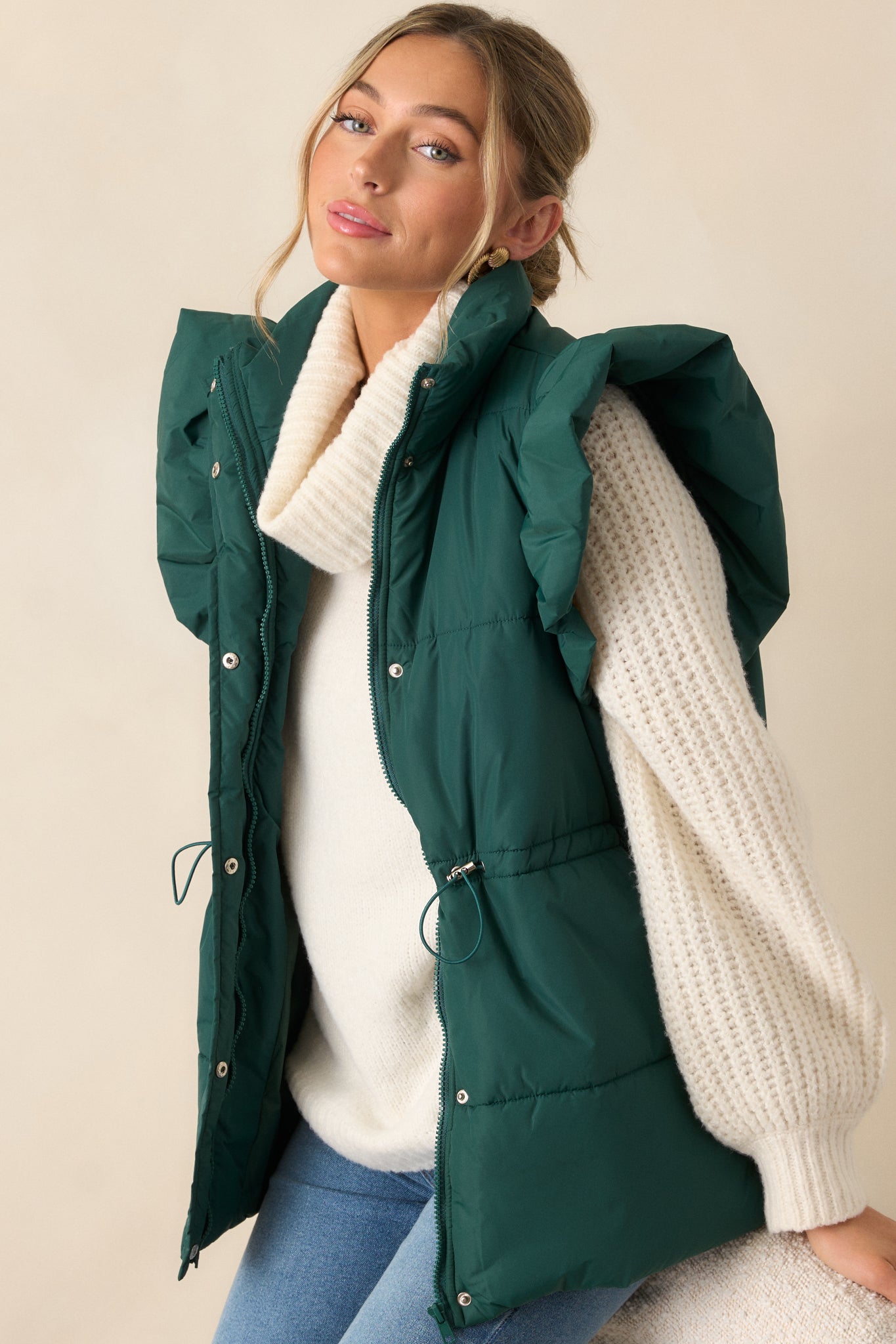 Close-up of the forest green puffer vest. The texture of the puffer detailing is clearly visible, with the sleeves’ soft, voluminous design creating a striking contrast against the sleek body of the vest.