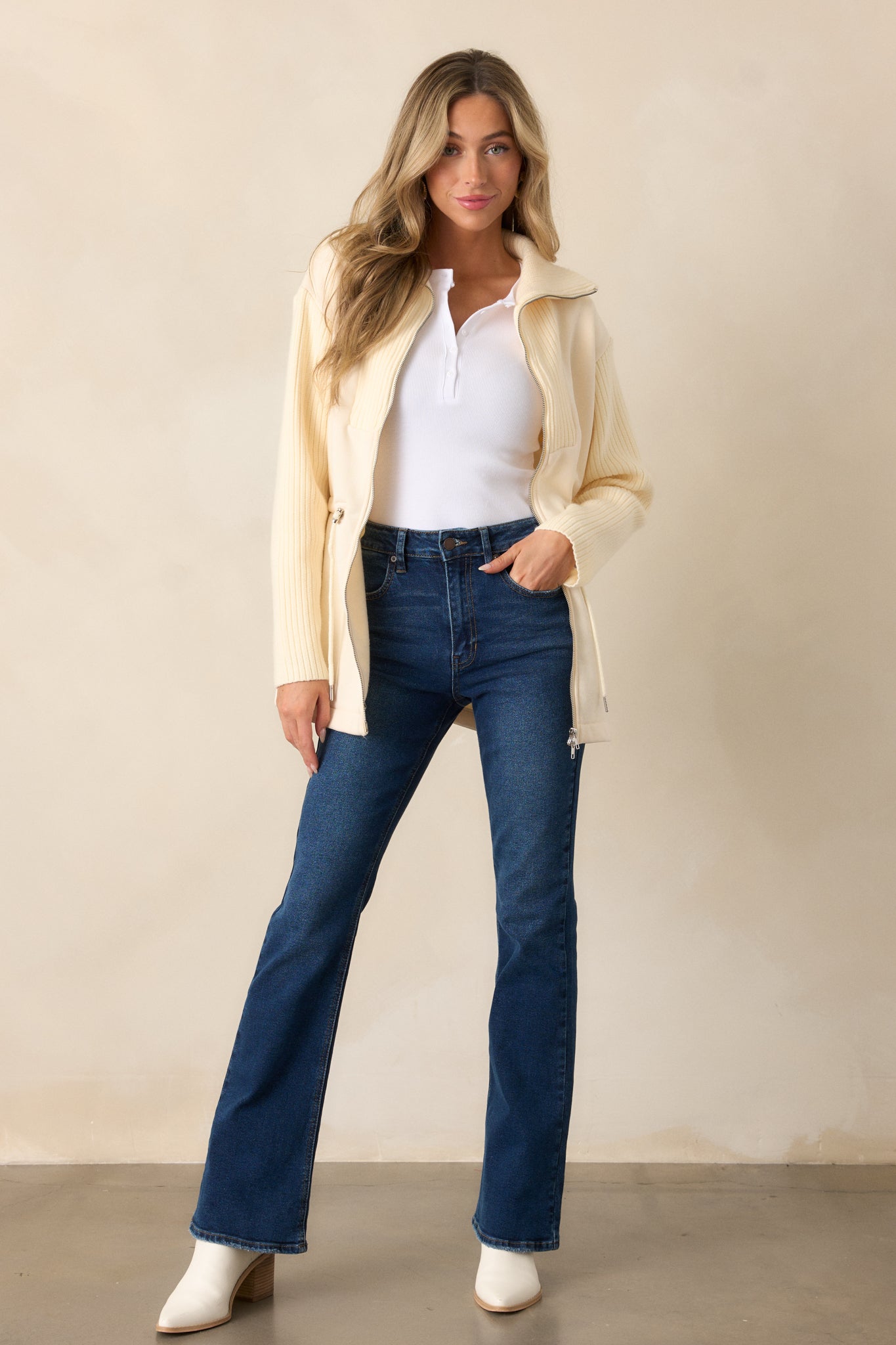 A full-length view of the high-waisted jeans showcasing the flared style and functional front pockets.