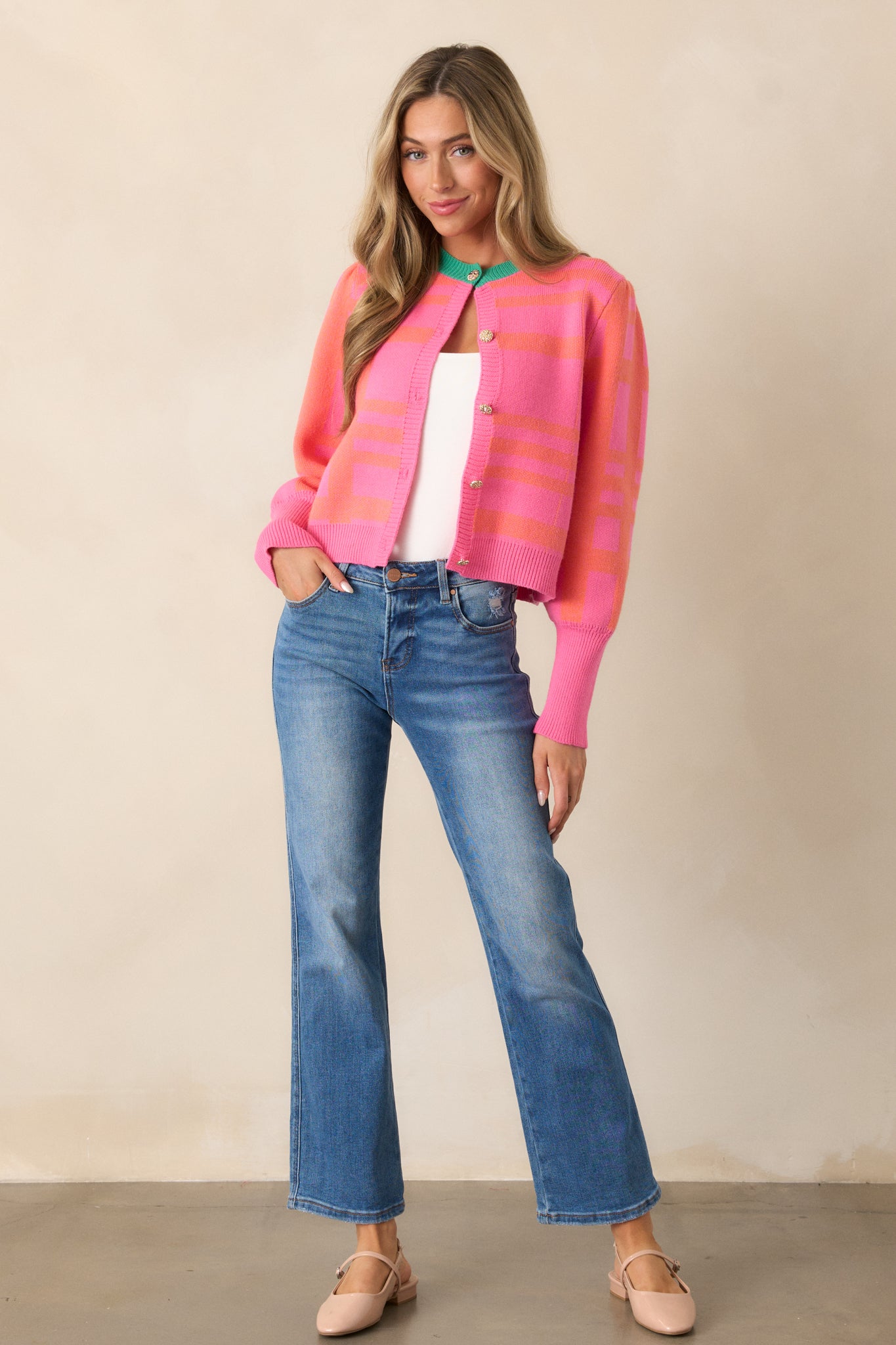 Full-length image of the pink cardigan, showcasing the gold embellished button front and the playful color-blocked design with contrasting stripes.