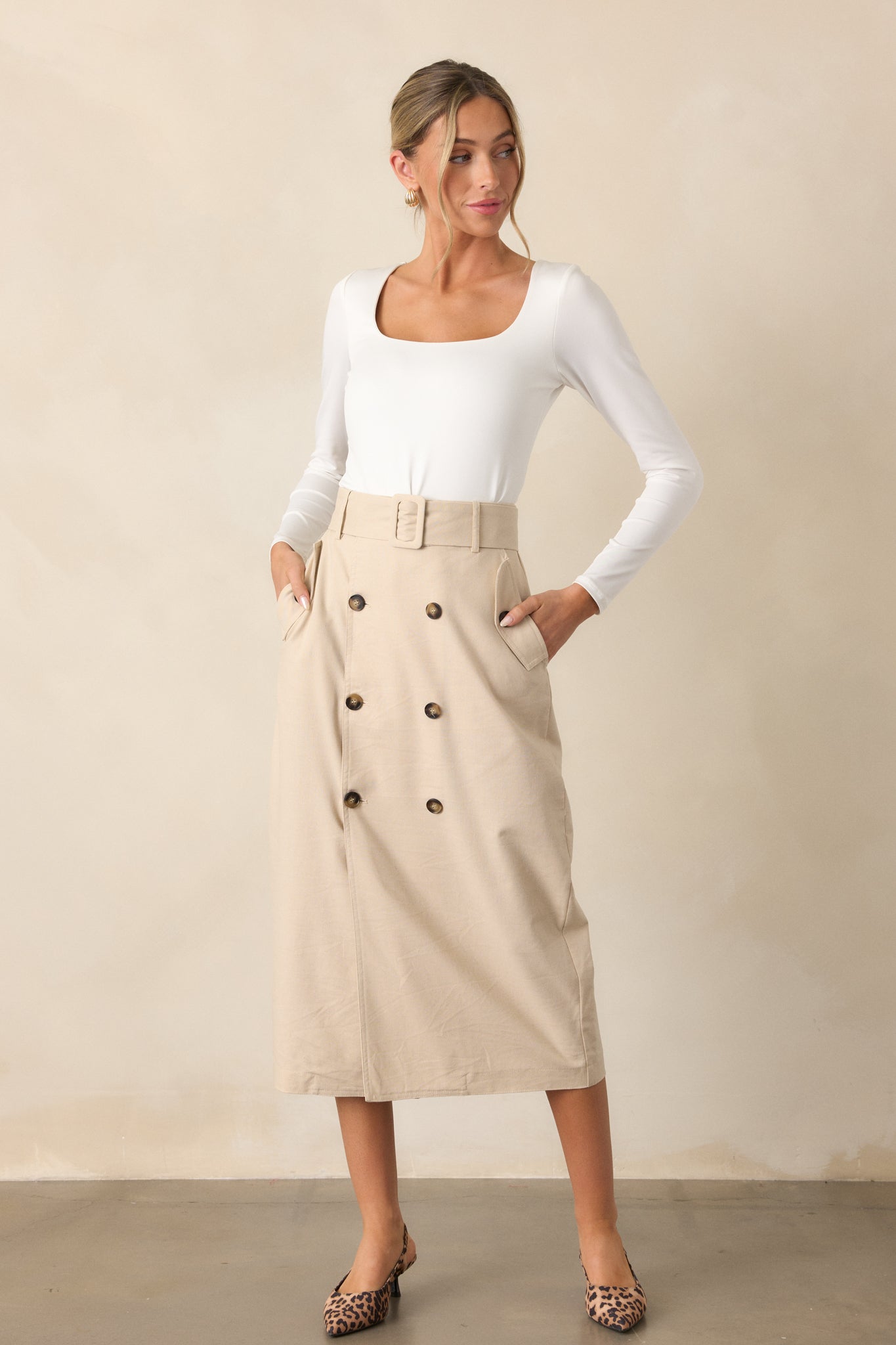 Full body view of a beige maxi skirt with a high-waisted design, square fabric belt, functional hip pockets, and a front button closure.