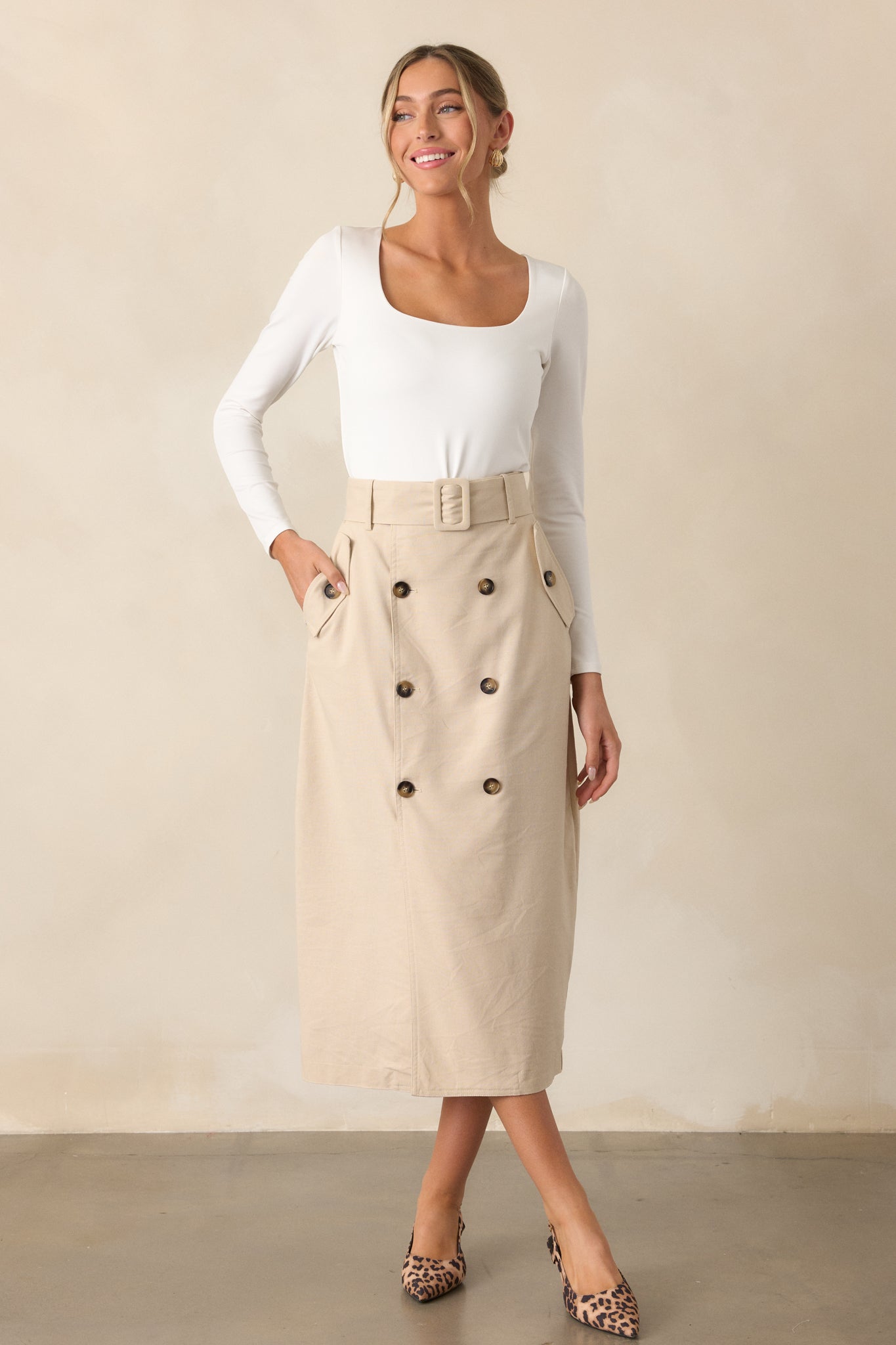 Wide shot of the beige maxi skirt featuring a high waist with an elastic insert, front buttons, and an open leg. The functional hip pockets add a practical touch.