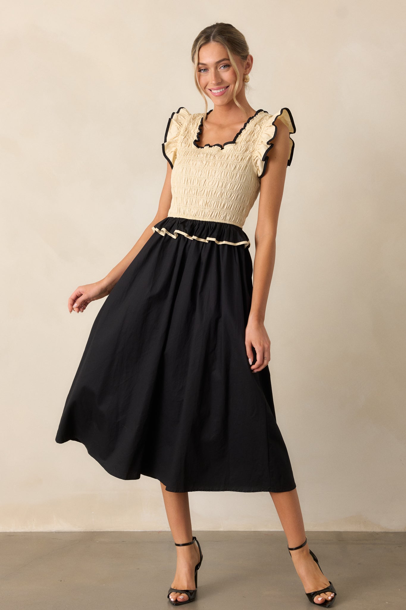 A full-length view of the bold dress showcasing its unique smocked top and alternating ivory and black design that flows to the hem.