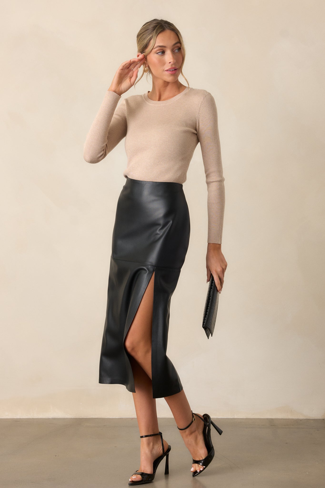 A black midi skirt with a high-waist design, fitted hip, and side slit is shown in a full-body front view.