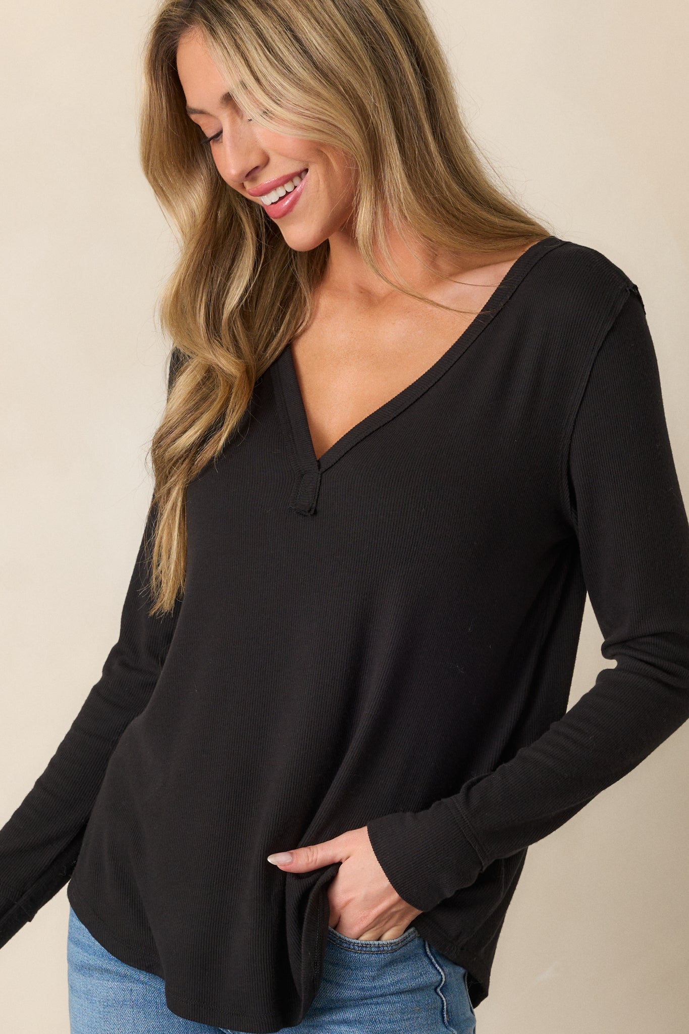 Close-up of the curved bottom hem of the black top, highlighting the soft ribbed fabric and flattering silhouette.