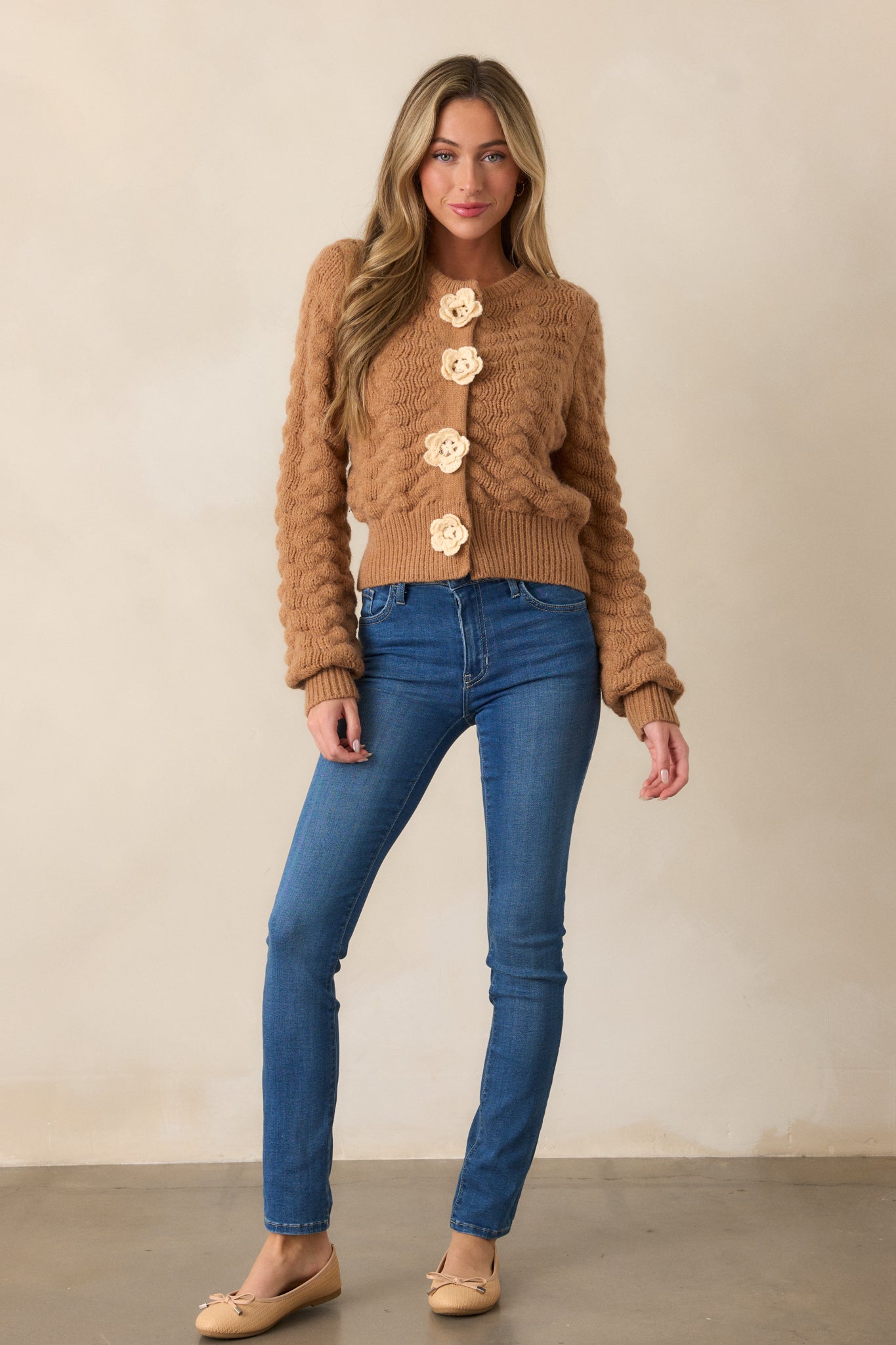 A full-length view of the honey cardigan, showcasing its rounded neckline, cable knit design, and long sleeves with ribbed cuffs.