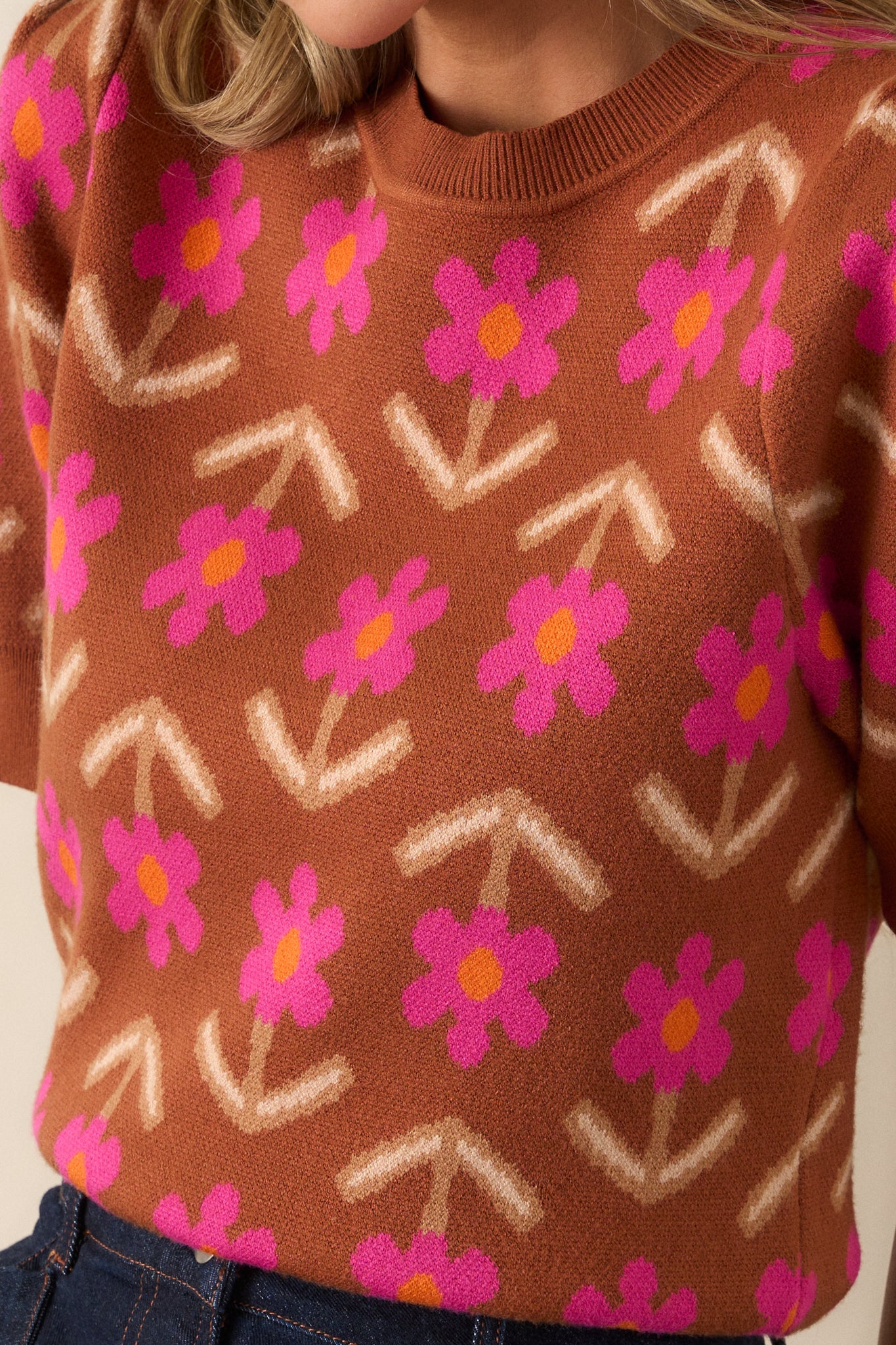 Close-up of the cinnamon sweater’s fabric, showing the texture of the geometric floral design and ribbed knit details on the hemline.