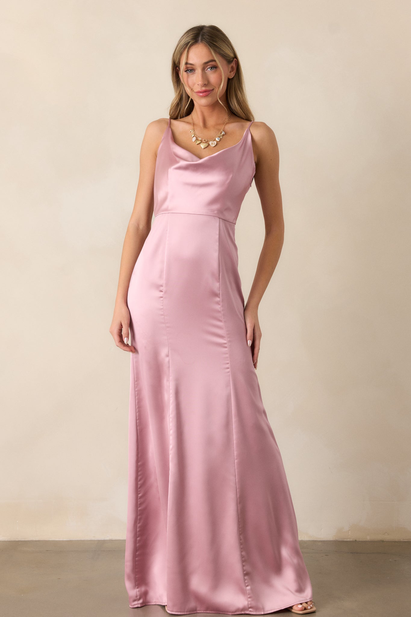 A blush maxi dress with a draped neckline, shown in a flowing silhouette that highlights the soft, elegant fabric and adjustable straps.