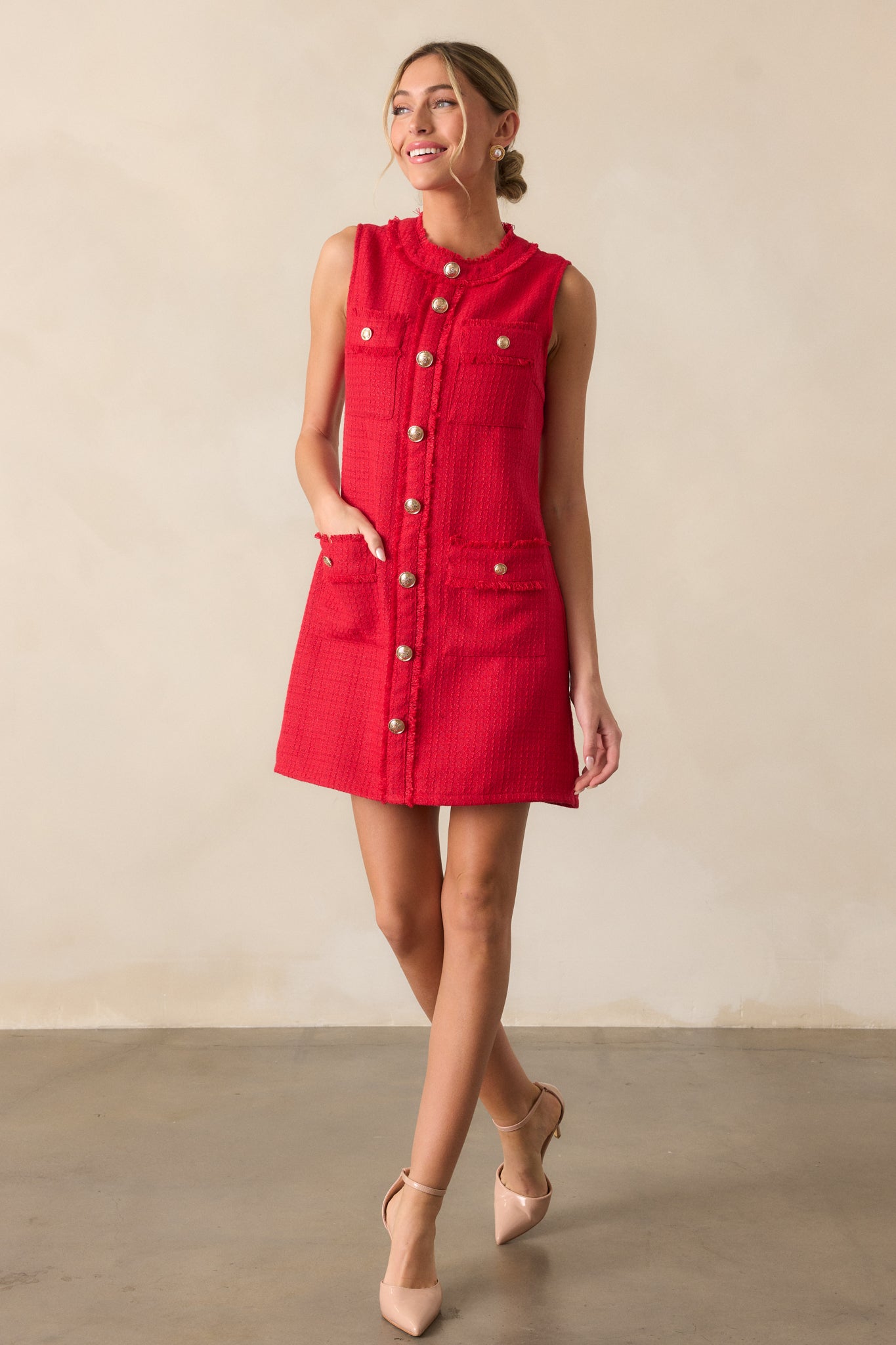 A full-length view of the red mini dress, highlighting its high rounded neckline, sleeveless design, and functional four pocket detailing.