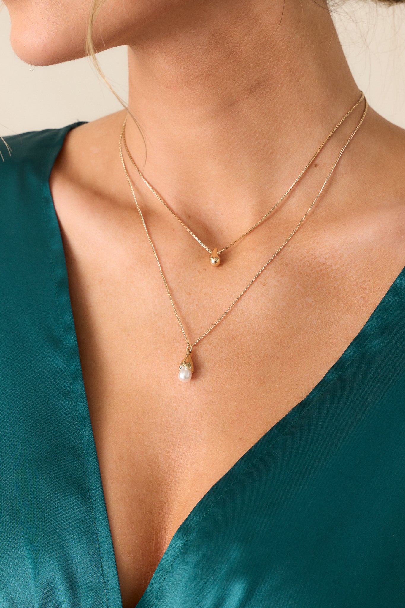 A zoomed-in shot highlighting both necklaces together, emphasizing the gold hardware, lobster clasp closure, and the intricate details of the teardrop charms.