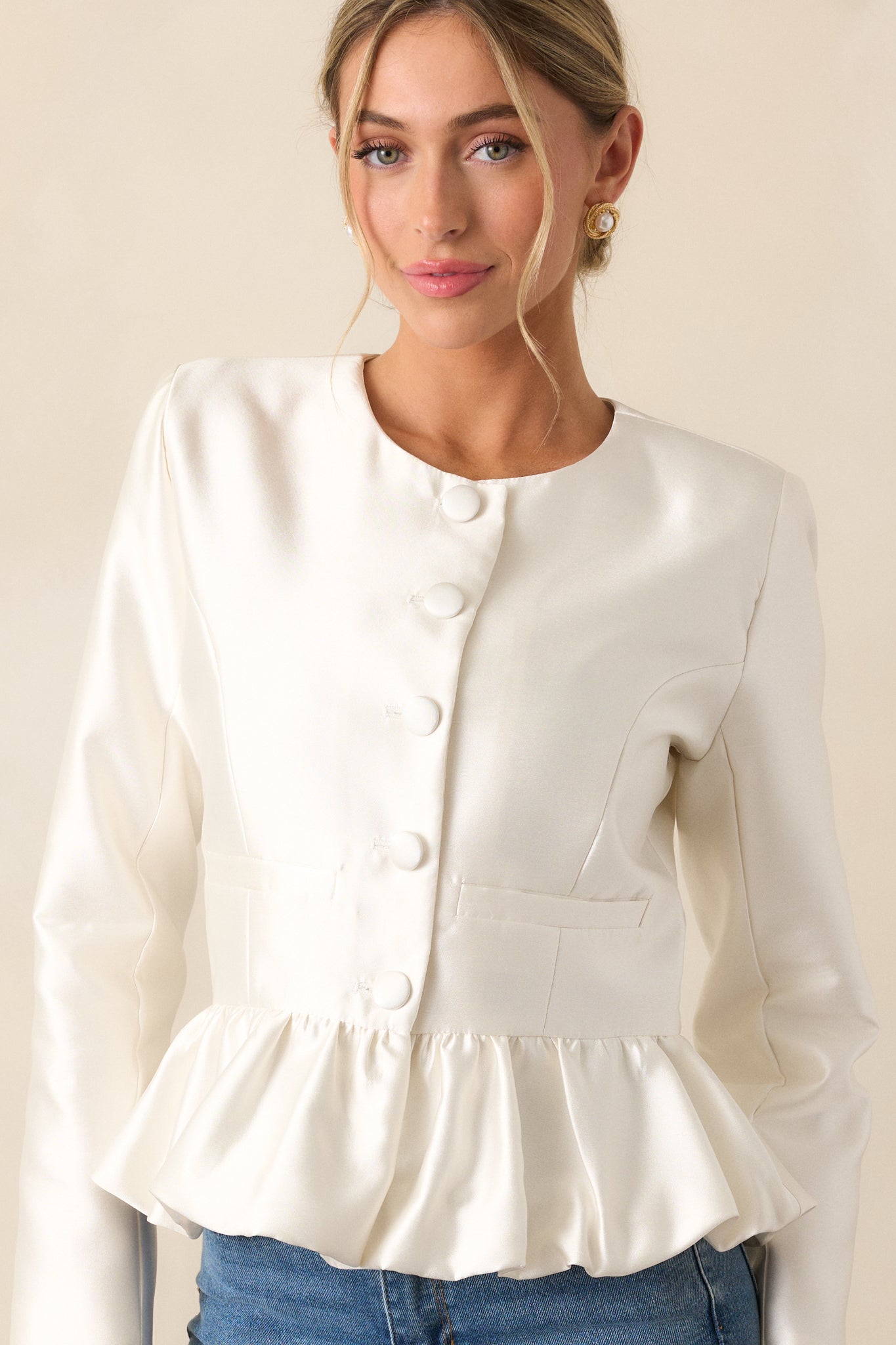 Detail shot of the ivory top's peplum silhouette and thick satin material, capturing the fabric's sheen and structure.