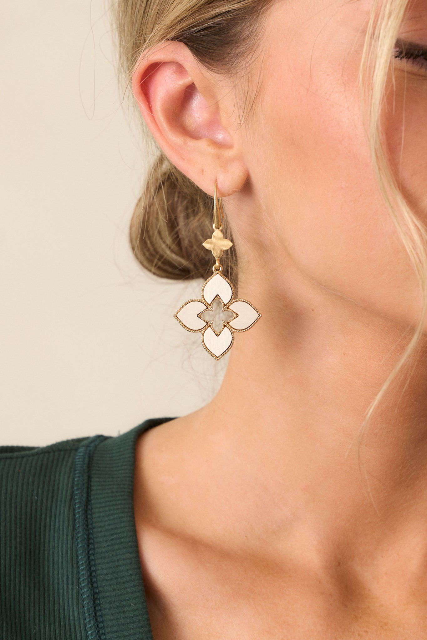 A front view of the earrings highlighting the drop design and the fish hook backing with the ivory and gold quatrefoil pendants.