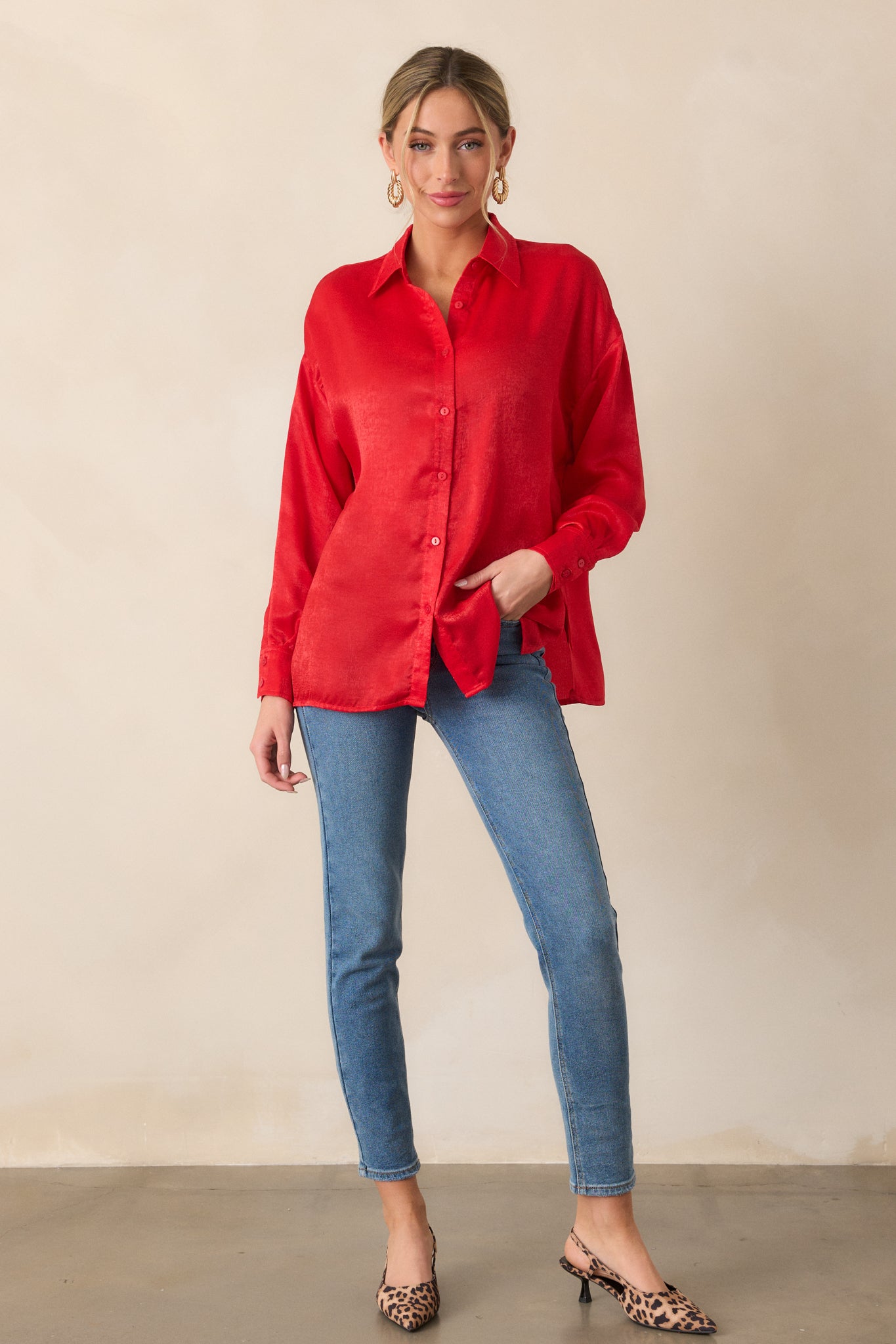 A full-body view of the red top featuring a collared neckline, buttons down the front, and a relaxed fit. The long sleeves have button cuffs, and the top drapes loosely.