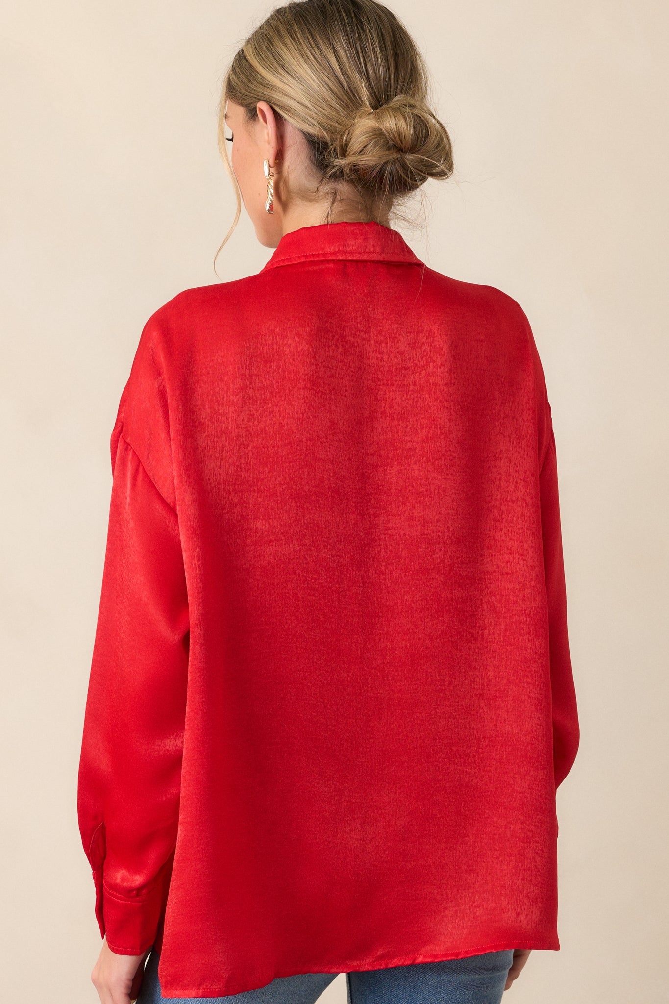 A back view of the red top showing the clean lines and relaxed fit, with a glimpse of the button details on the cuffs of the sleeves.