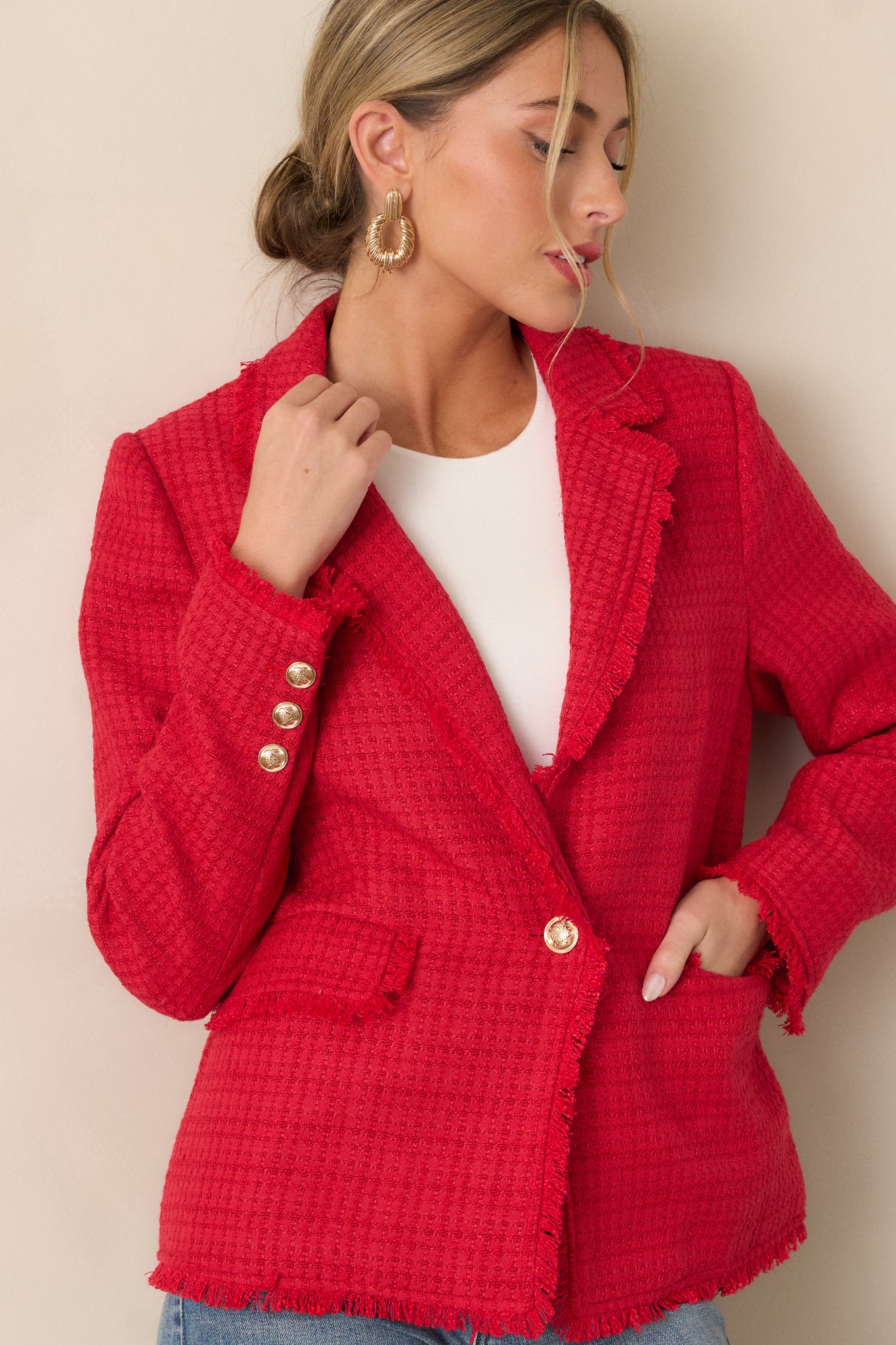 A cropped image showing the lapel collar neckline and the intricate gold embellished buttons on the blazer.