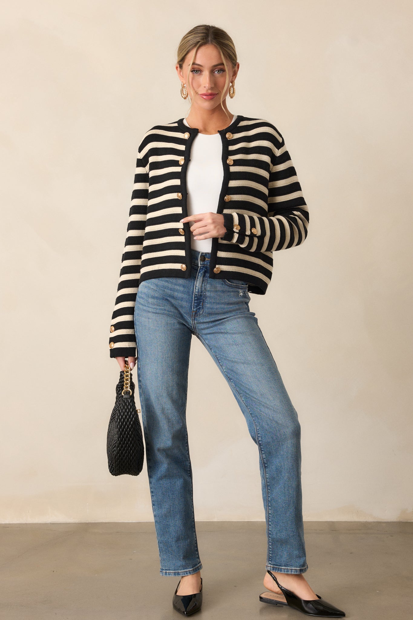 Front view of the black cardigan, showcasing the rounded neckline, faux gold-embellished button detailing, and tan and black striped design.