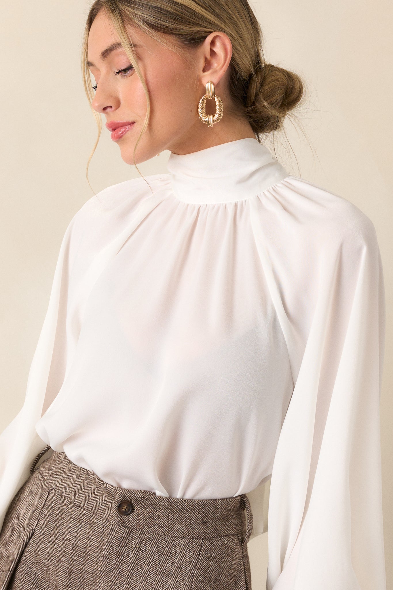 A cropped shot displaying the balloon sleeves and high neckline, showcasing the fabric texture and the delicate flow of the white top.