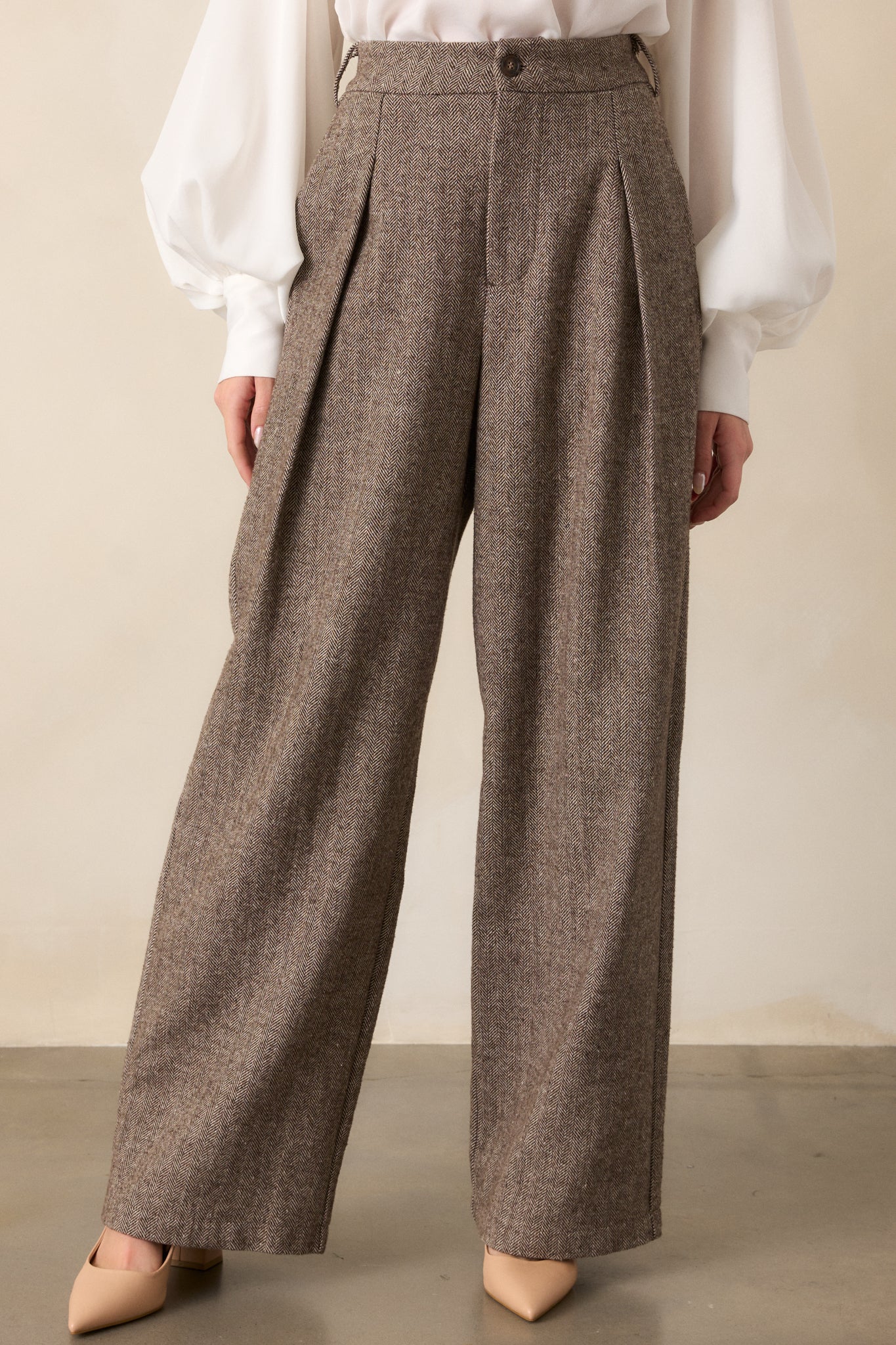 A cropped view of the lower half of the brown pants, emphasizing the clean lines of the herringbone design and the crisp hem. The structure and quality of the fabric are evident in this shot.