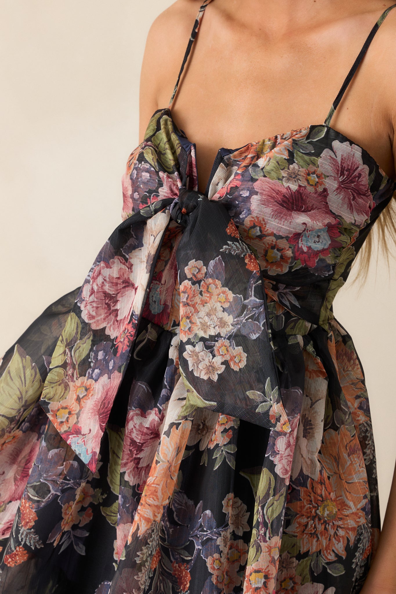 Close-up of the floral design on the navy dress, highlighting the intricate patterns and the self-tie accent at the notch neckline.