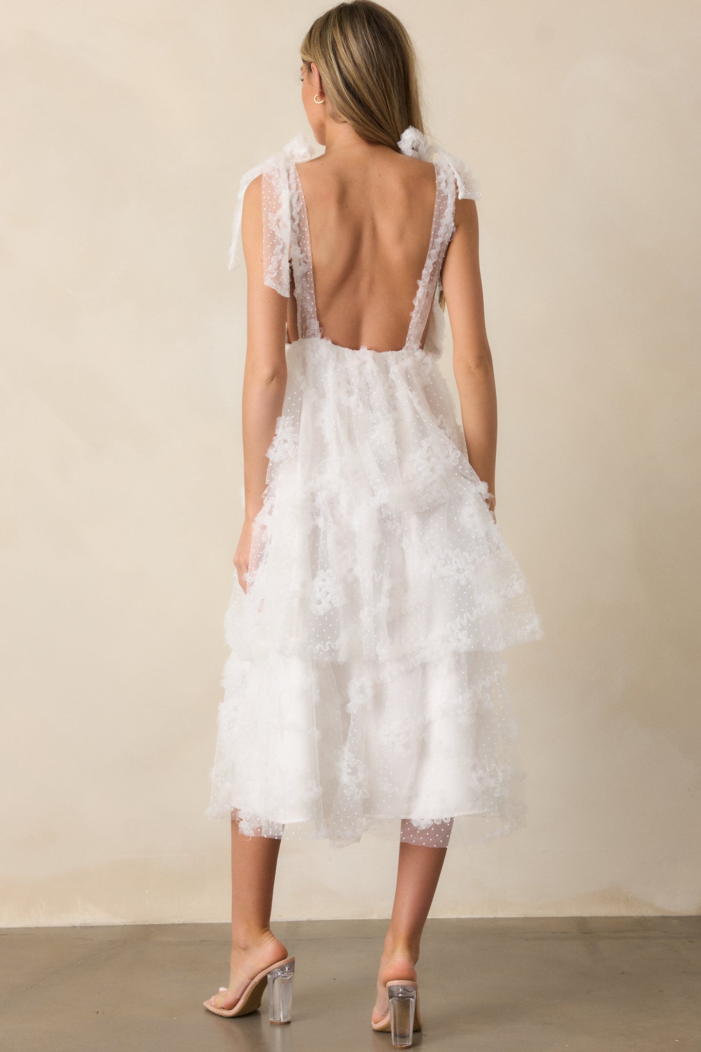 Back view of the dress, showing the adjustable self-tie shoulder straps and the flow of the tiered skirt, with the deep v-neckline visible from the back.