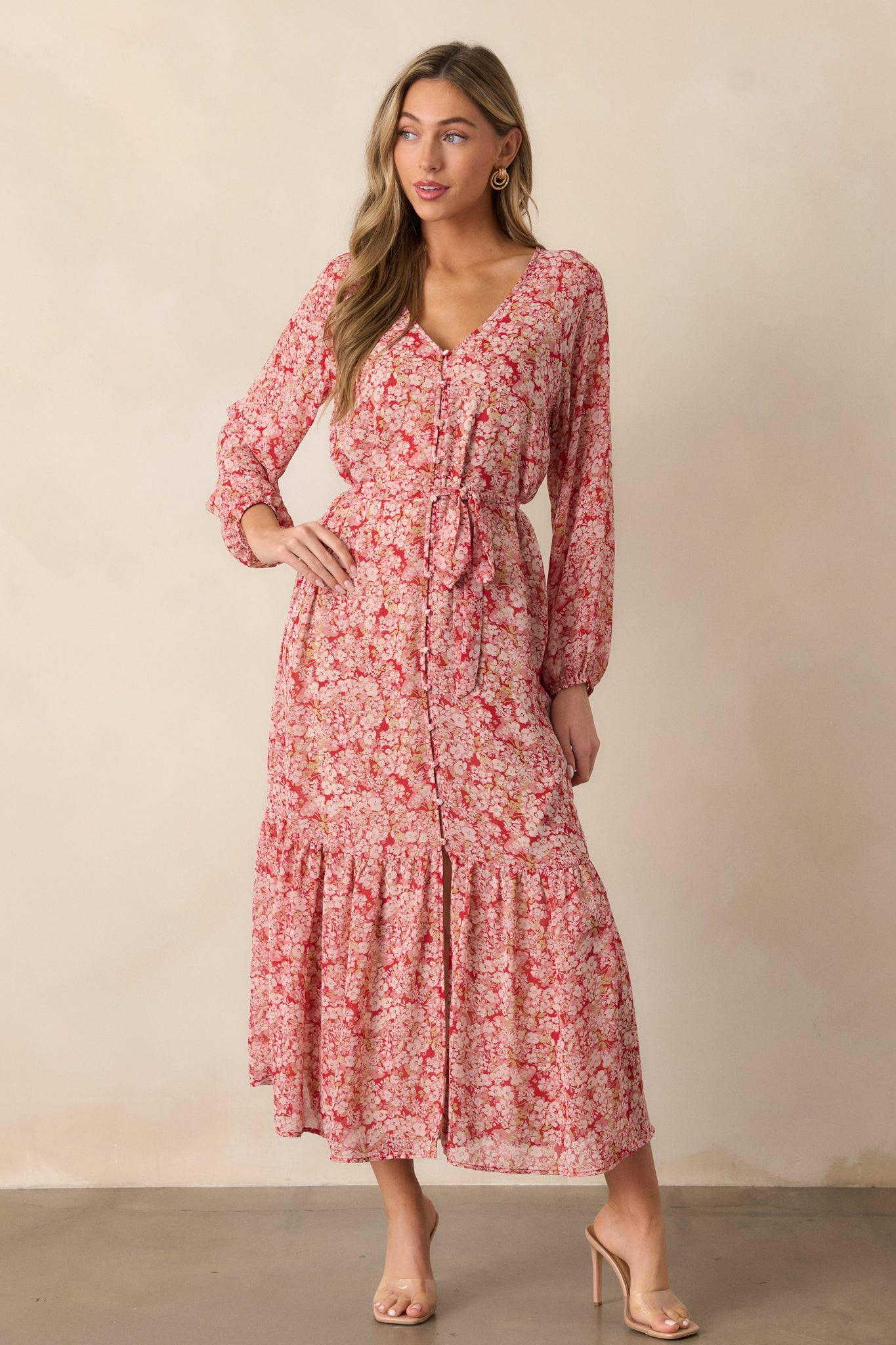 Front view of the cranberry dress, highlighting the v-neckline, floral print, and long sleeves, paired with a self-tie waistband and tiered midi-length skirt.