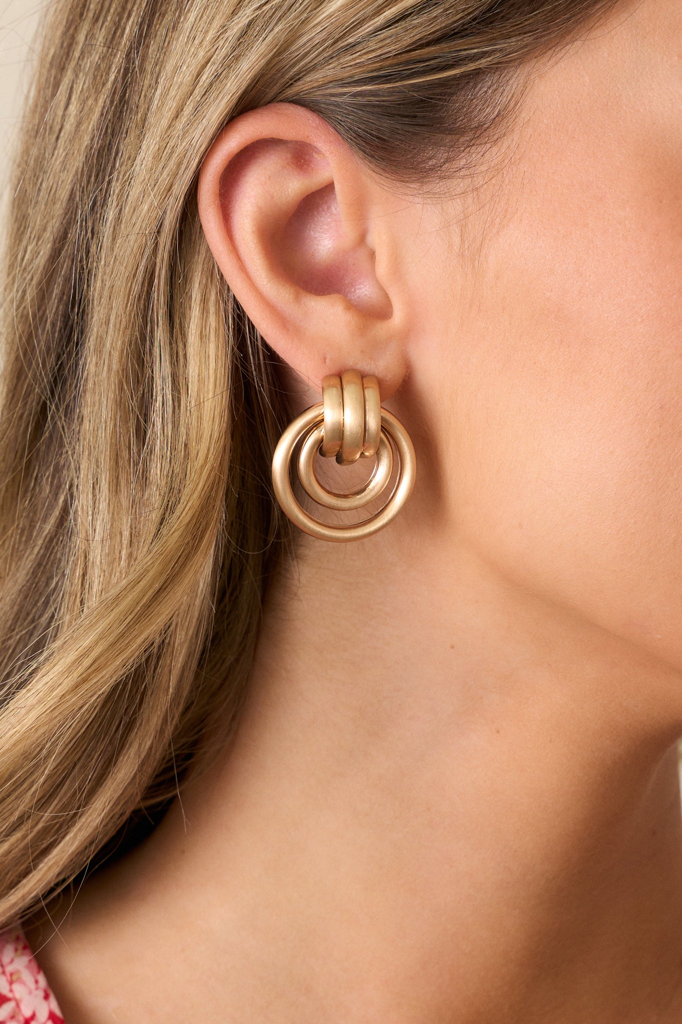 Close-up of gold drop earrings featuring a hoop design with gold hardware and secure back postings.