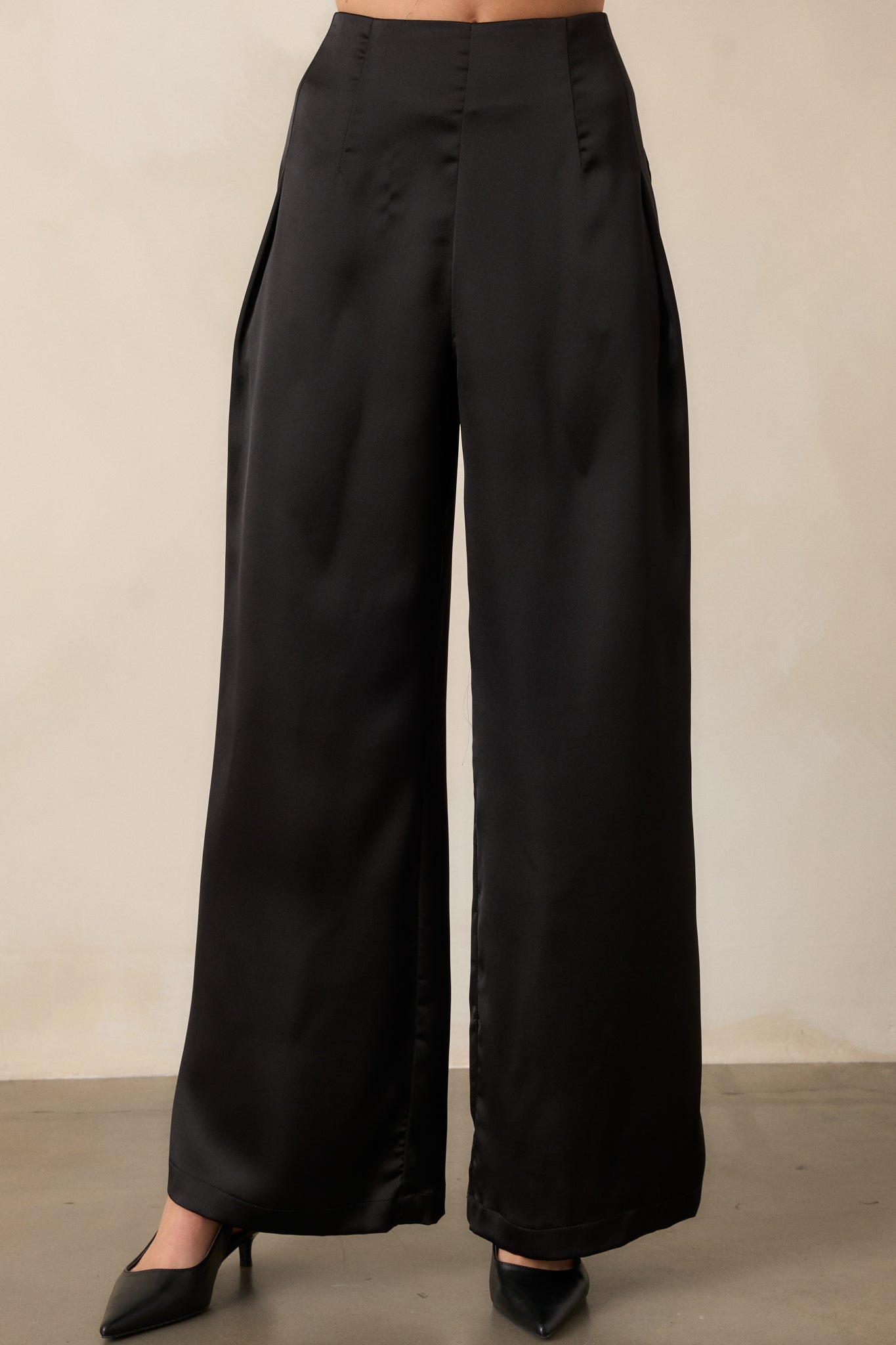 Detailed view of the wide leg design of the black pants, showing the flowy satin fabric from the knee down to the full length.