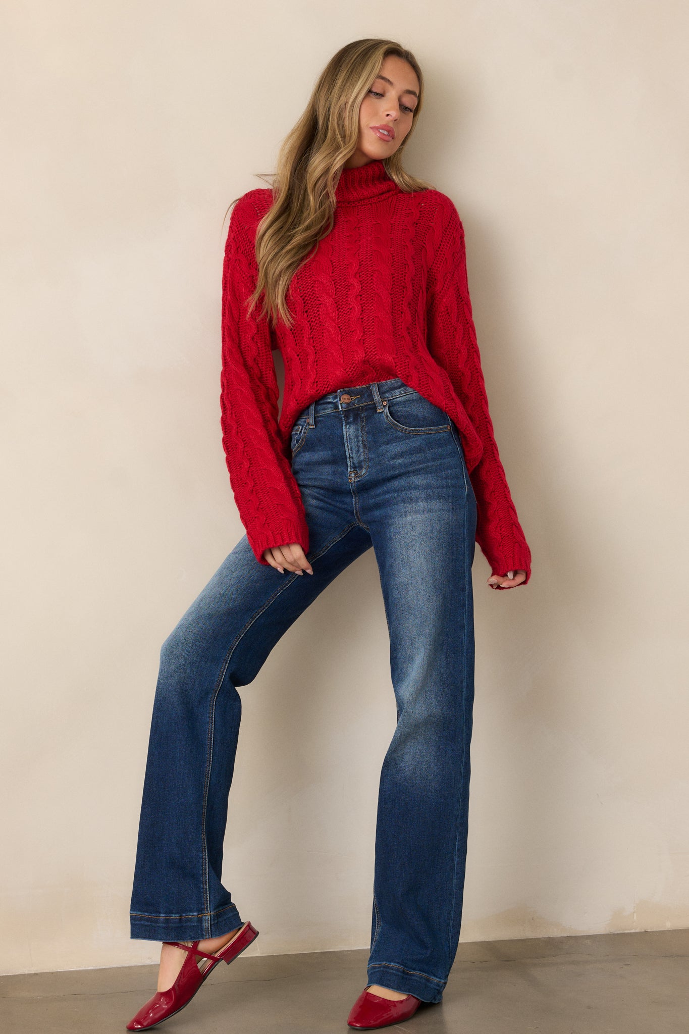 Front view of a red sweater with a turtle neck, featuring a beautiful cable knit design, long sleeves, and a relaxed fit.