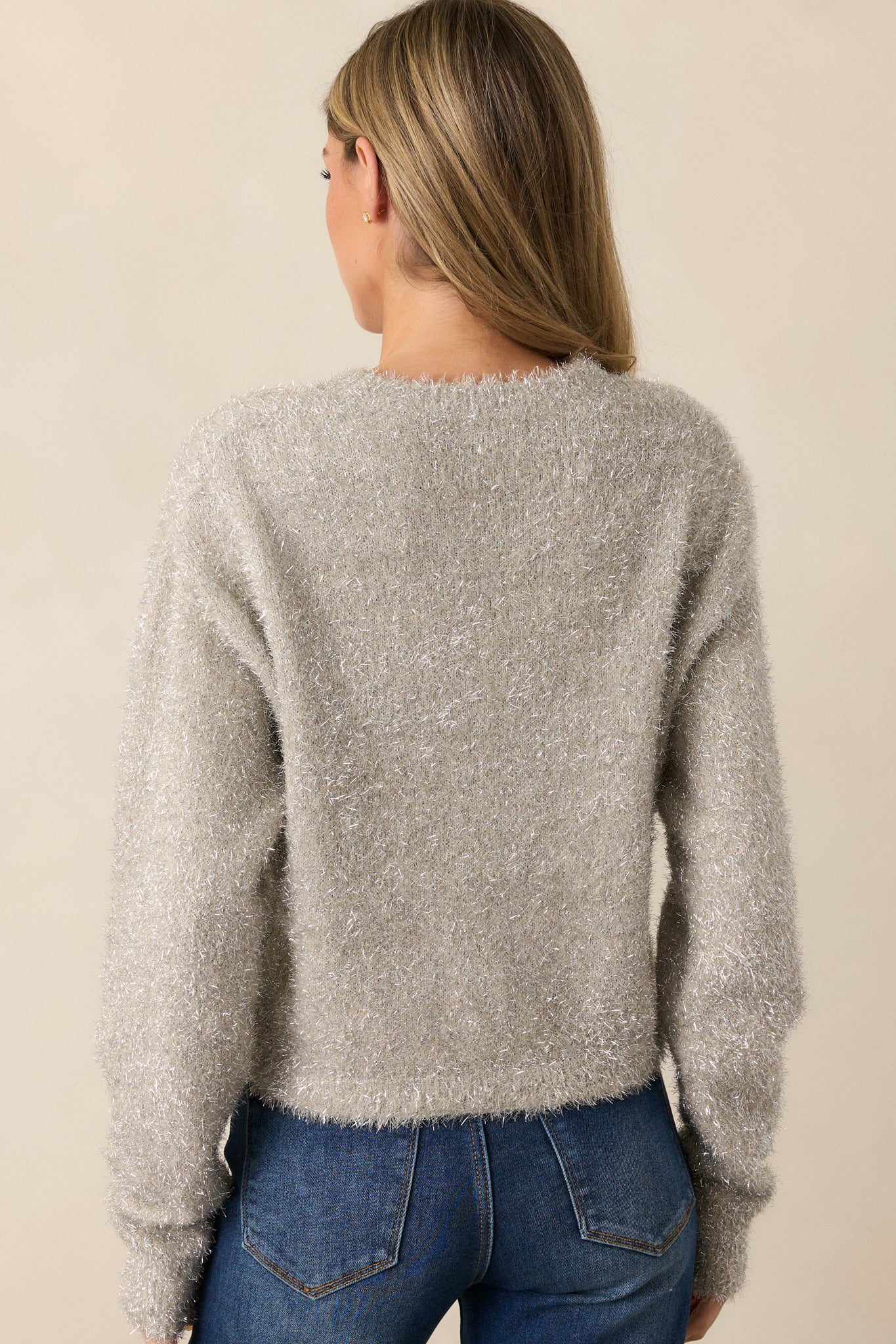 A back view of the champagne sweater, showing the cropped length and long sleeves, with the shiny silver tinsel fabric continuing around to create a consistent shimmering effect.