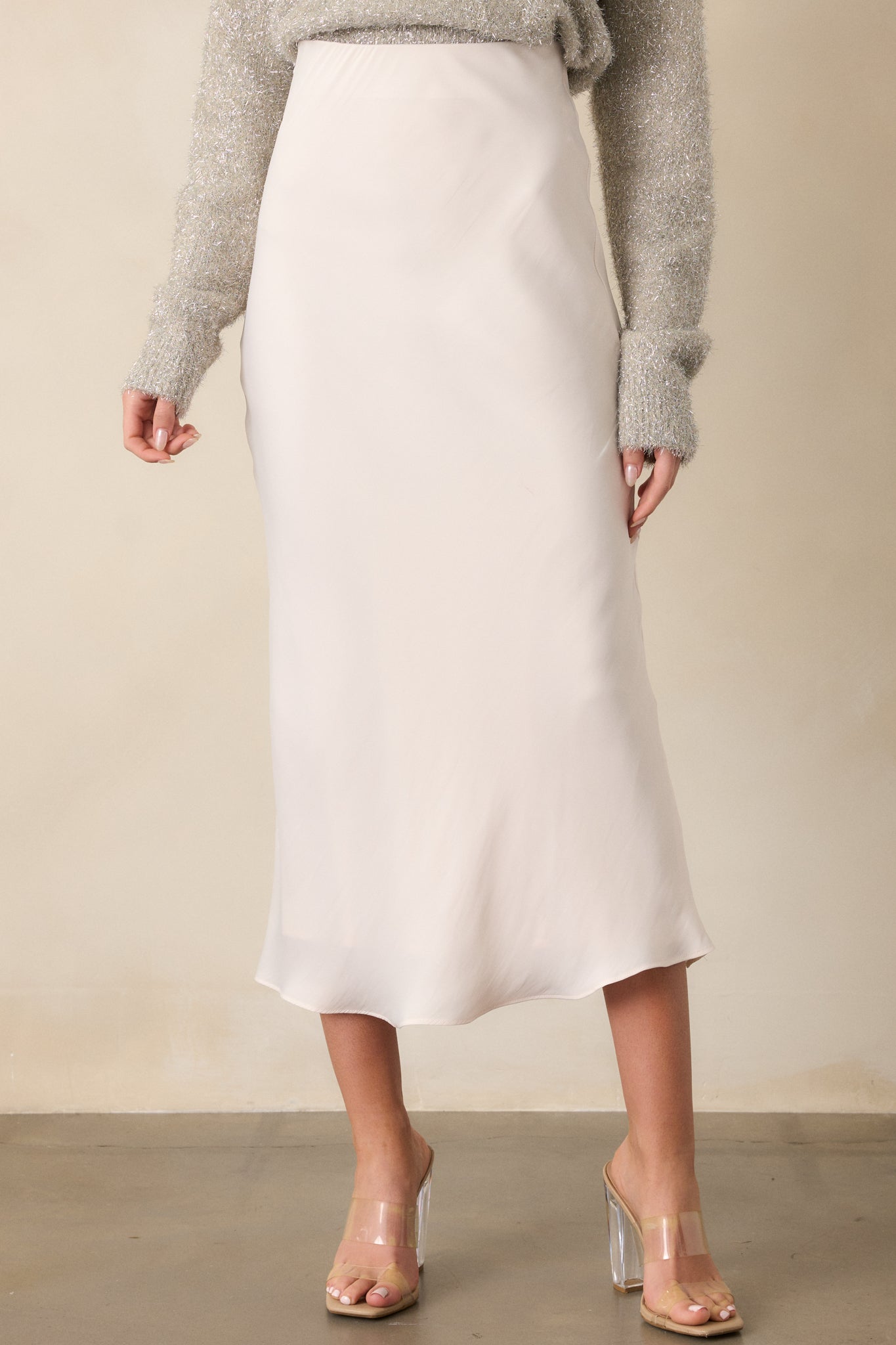 A cropped photo of the elastic waistband on the ivory skirt, showcasing the mid-rise fit and the way the satin fabric gathers elegantly around the waist for a flattering silhouette.