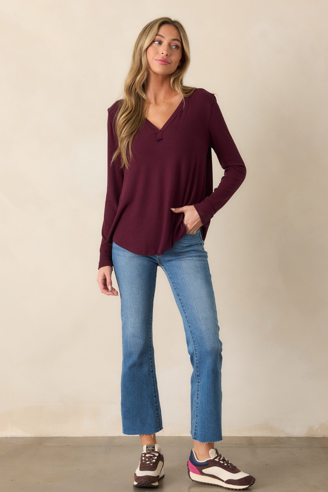 Front view of a berry top featuring a V-neckline, long sleeves, and a soft ribbed design with a curved bottom hem.