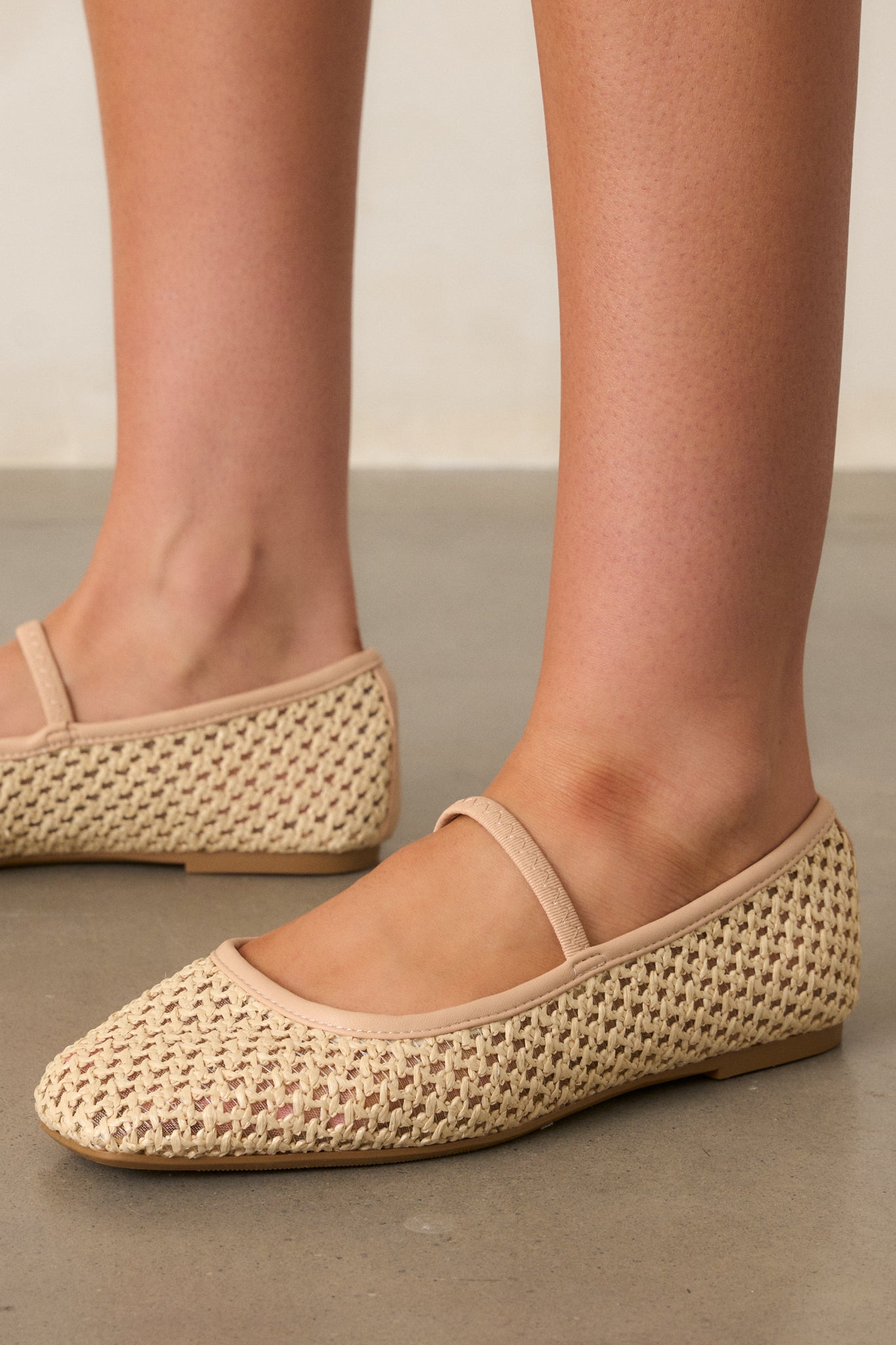 A detailed shot showcasing the textured woven material of the flats, with the elastic foot strap, beige trim, and square toe clearly visible.