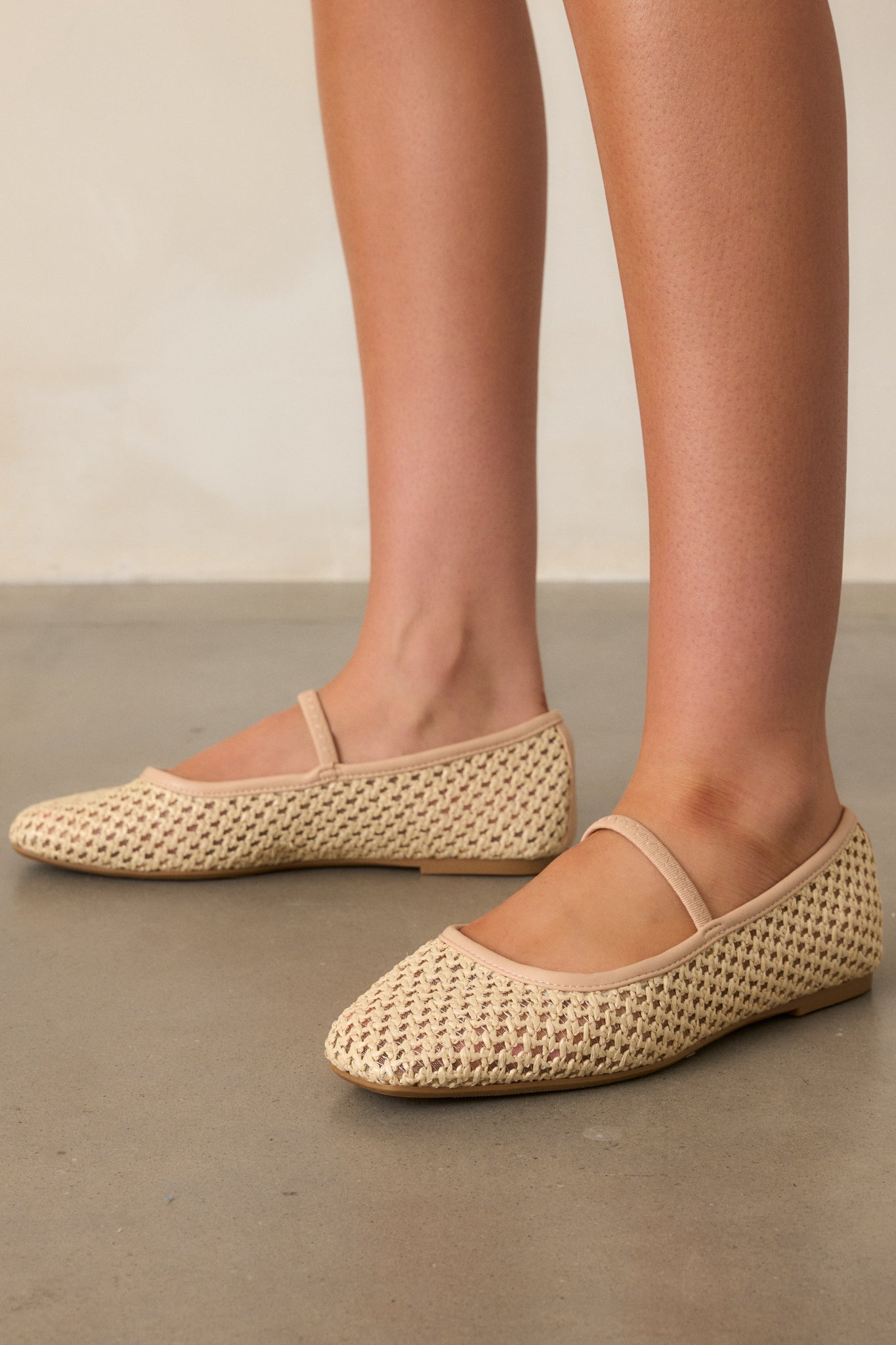 A cropped view of the woven flats, focusing on the square toe and elastic foot strap, with the beige trim and heel visible in the frame.