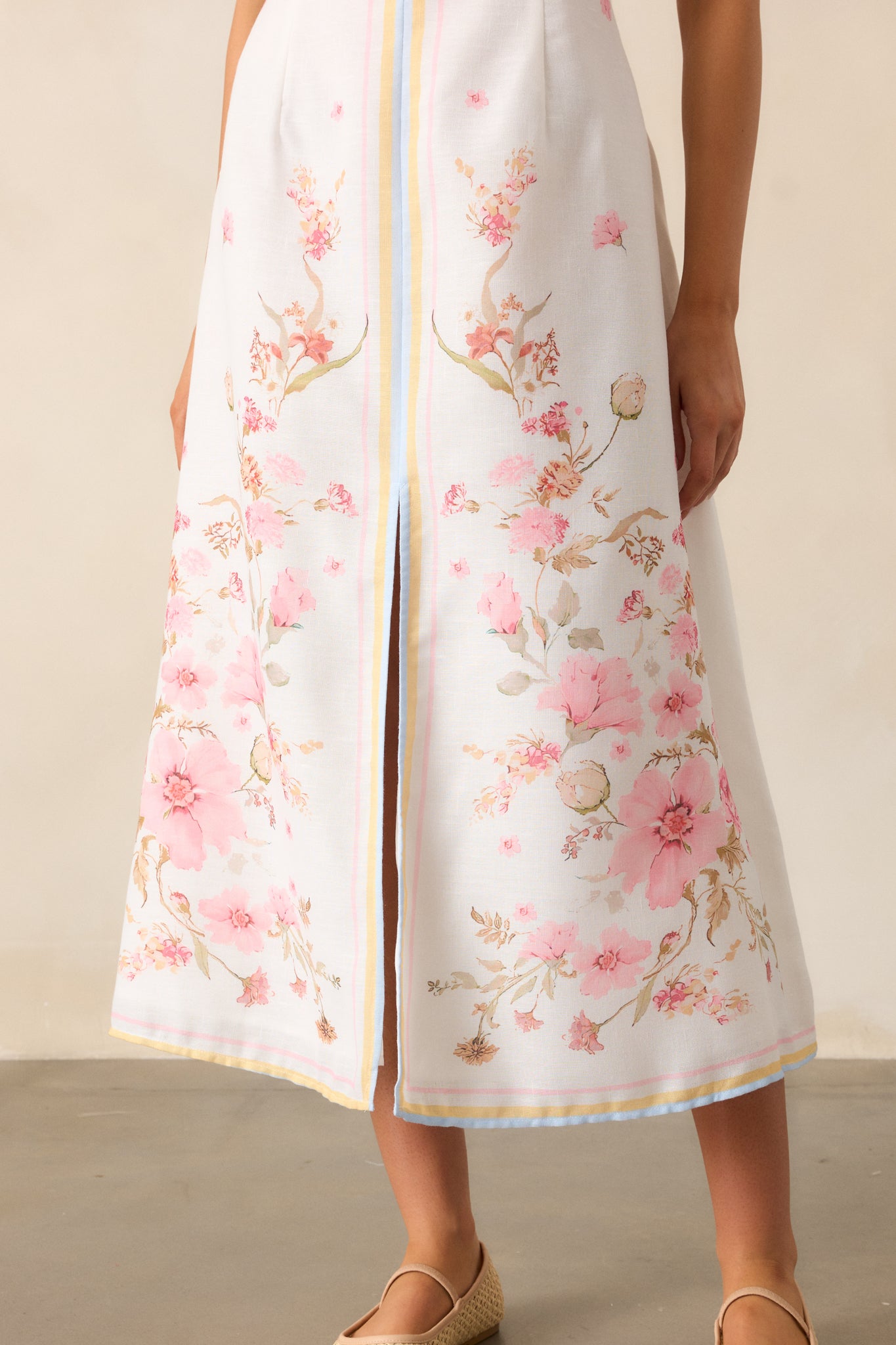 The skirt of this floral midi dress flows like a soft summer breeze, featuring a playful front slit and a delicate floral pattern that feels like a garden in motion.