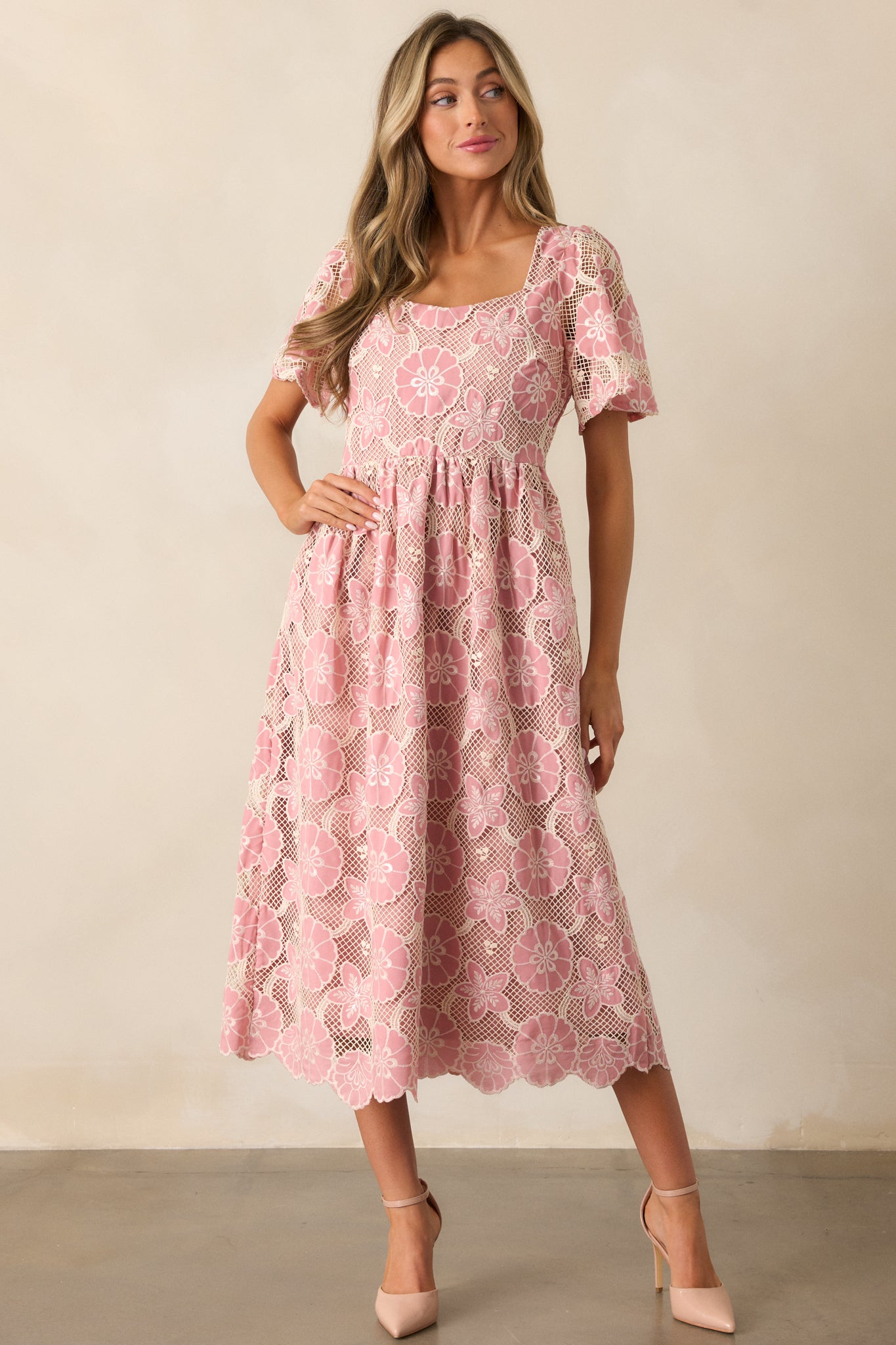 A full-length view of the pink dress, showcasing its straight neckline, embroidered floral design on the body, and sheer embroidered short sleeves.