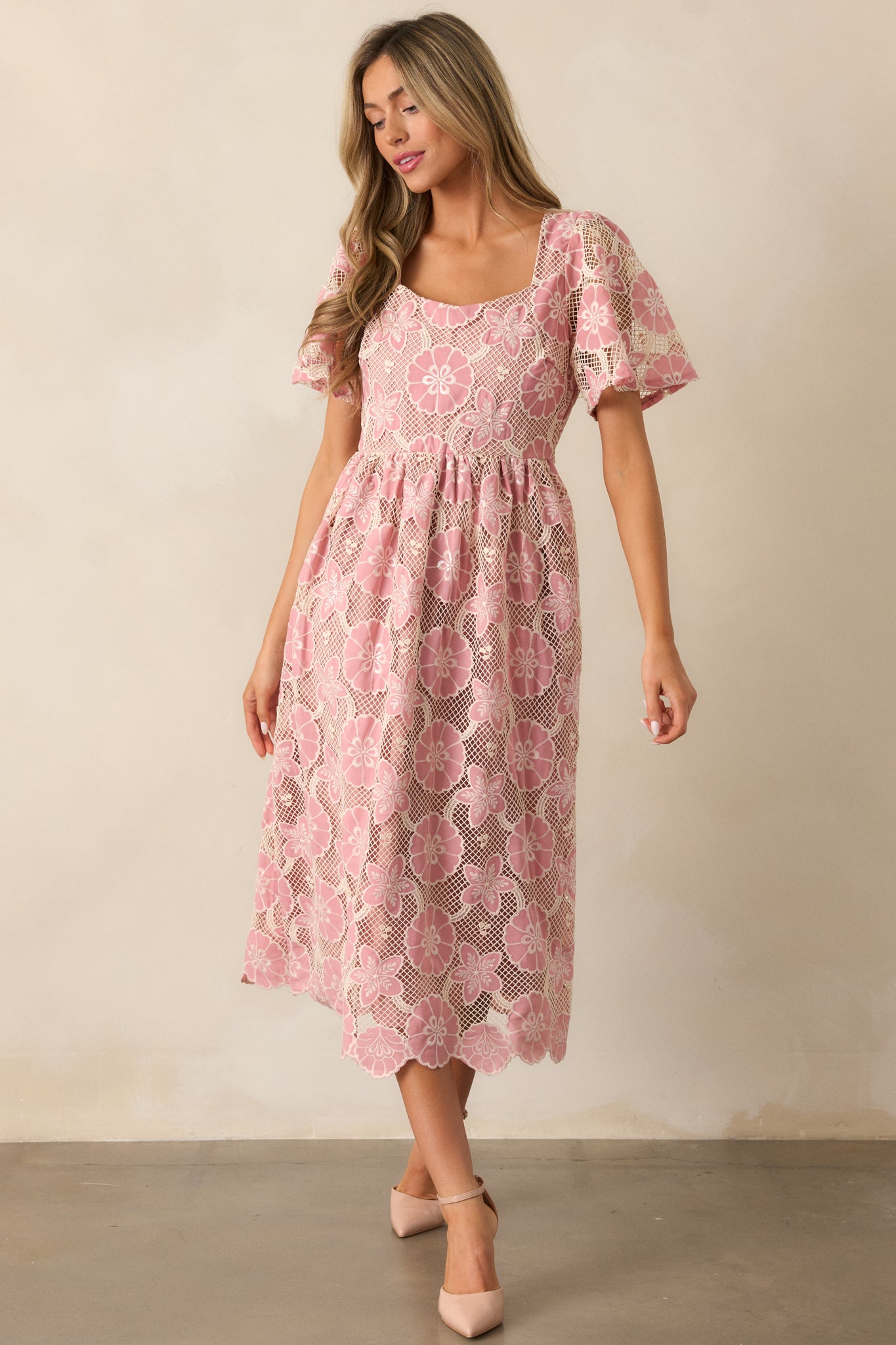 A front-facing shot of the pink dress with focus on the embroidered floral details along the bodice and the sheer short sleeves, emphasizing the dress's silhouette.