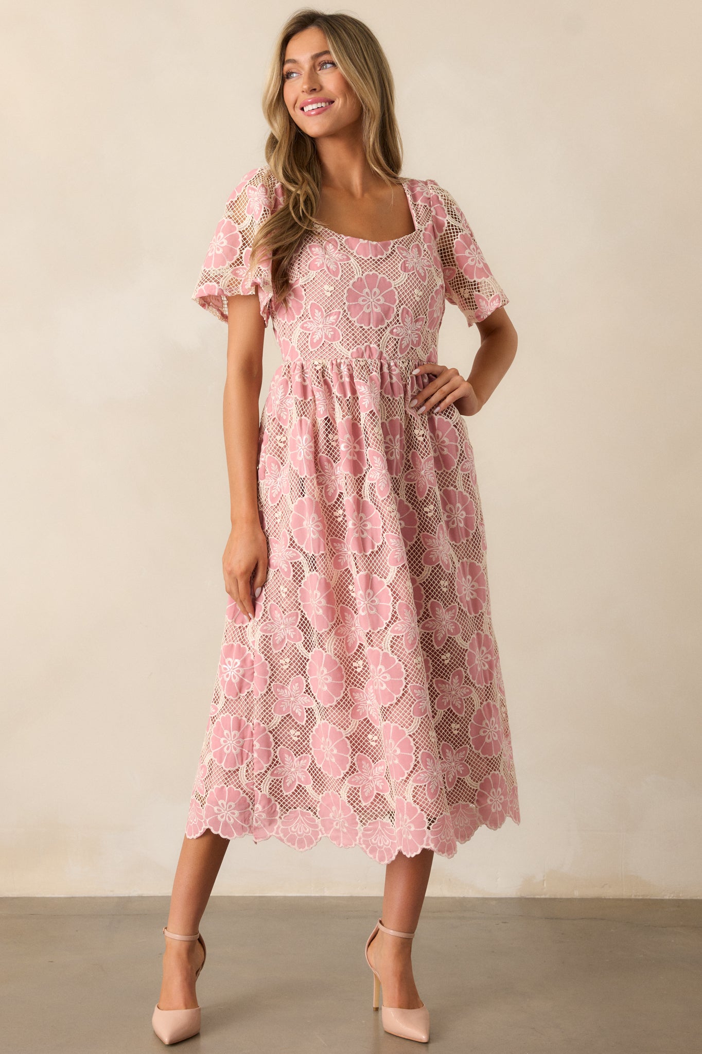 A shot of the pink dress, with emphasis on the sheer, embroidered short sleeves and the smooth, straight-cut neckline.